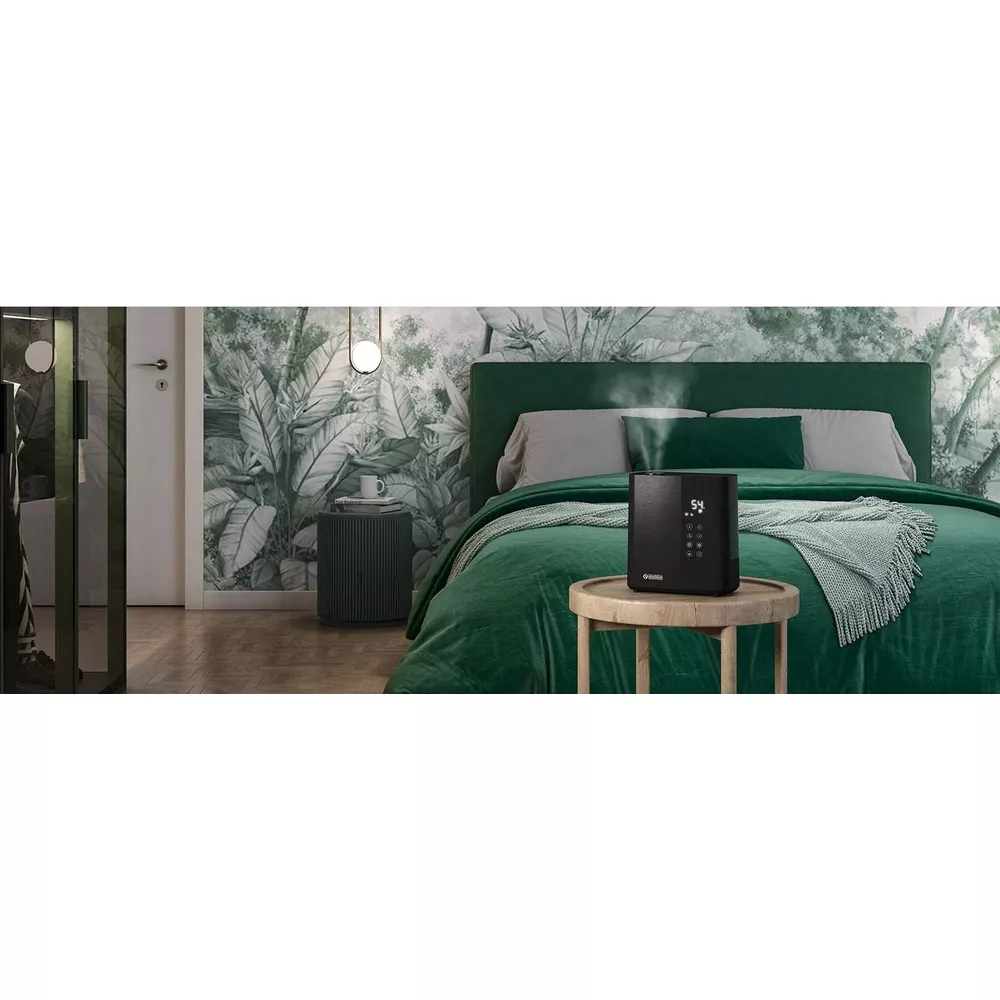 Un umidificatore nero emette vapore su un comodino in una camera da letto con murale tropicale.