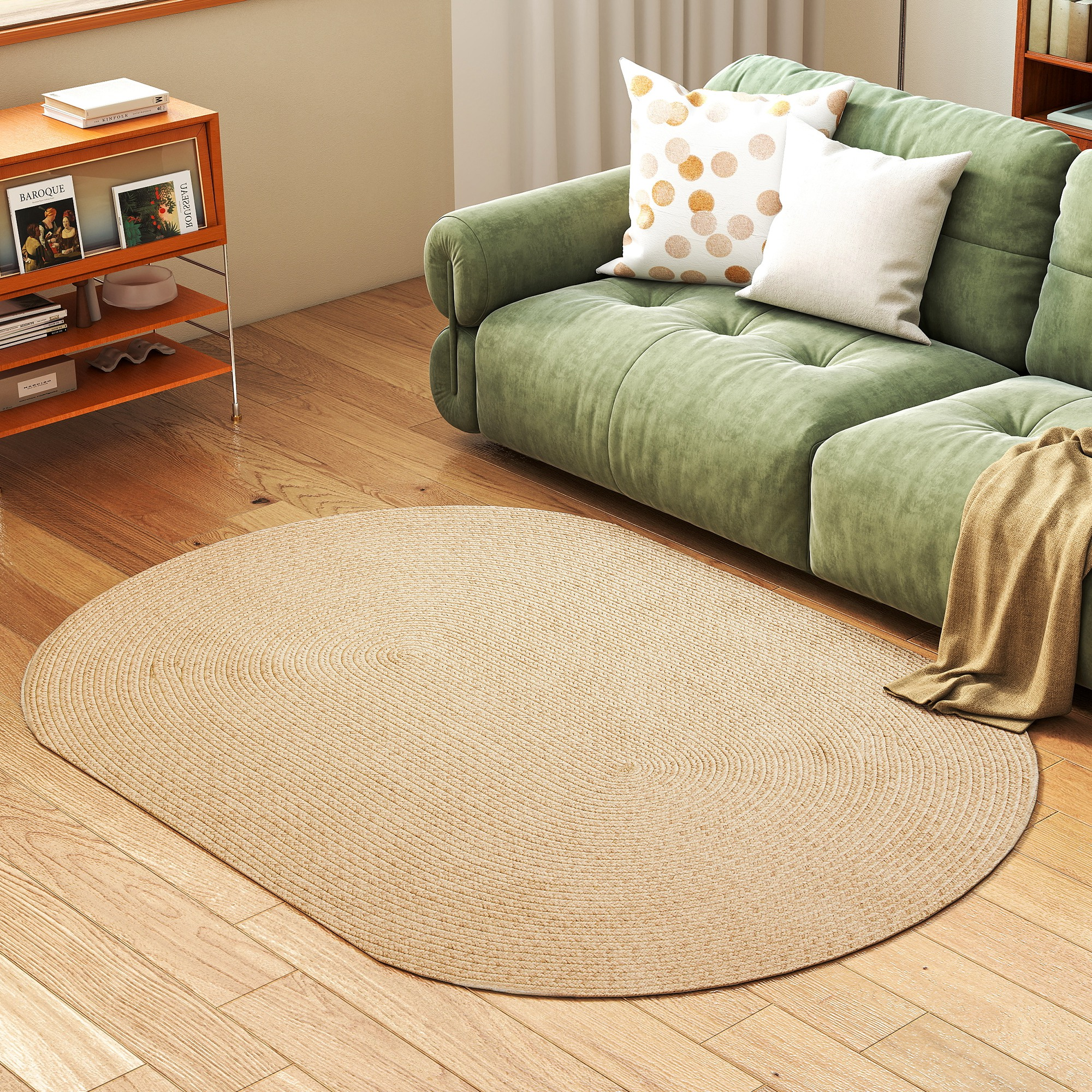 Sofá verde con cojines y manta sobre alfombra ovalada de fibra natural.