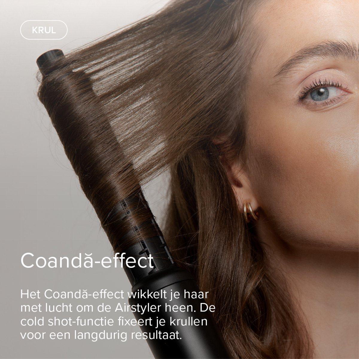 A woman styles her hair using a curling wand that creates a curl.