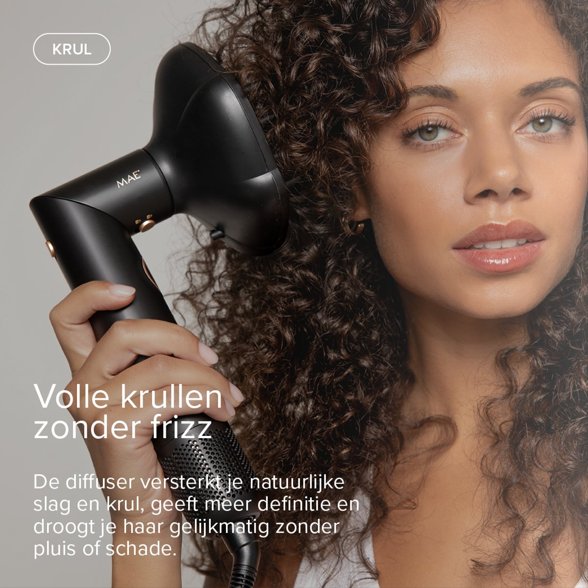 A woman with curly hair uses a black diffuser attachment on a hairdryer.