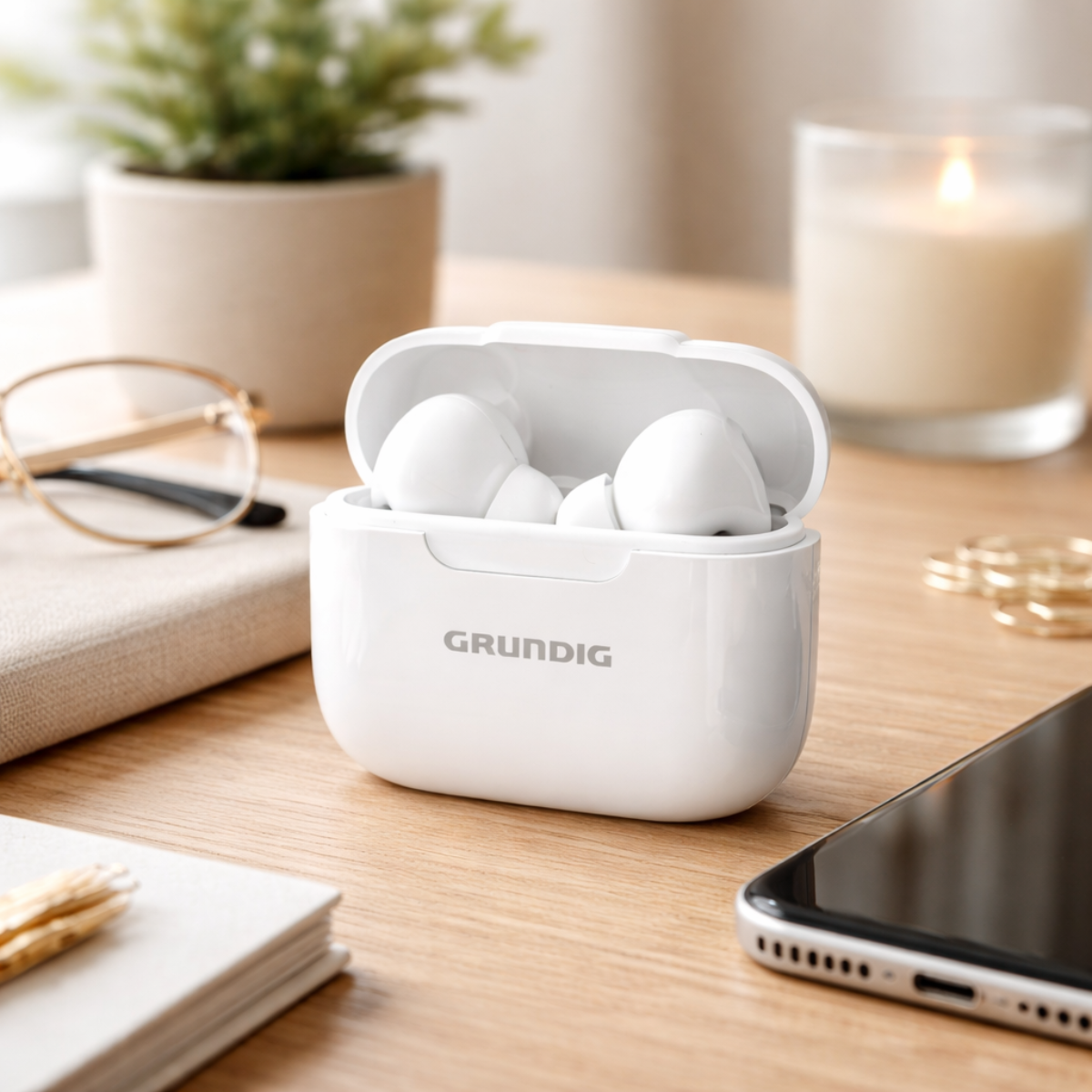 Witte GRUNDIG oordopjes in een oplaadcase op houten tafel met kaars.