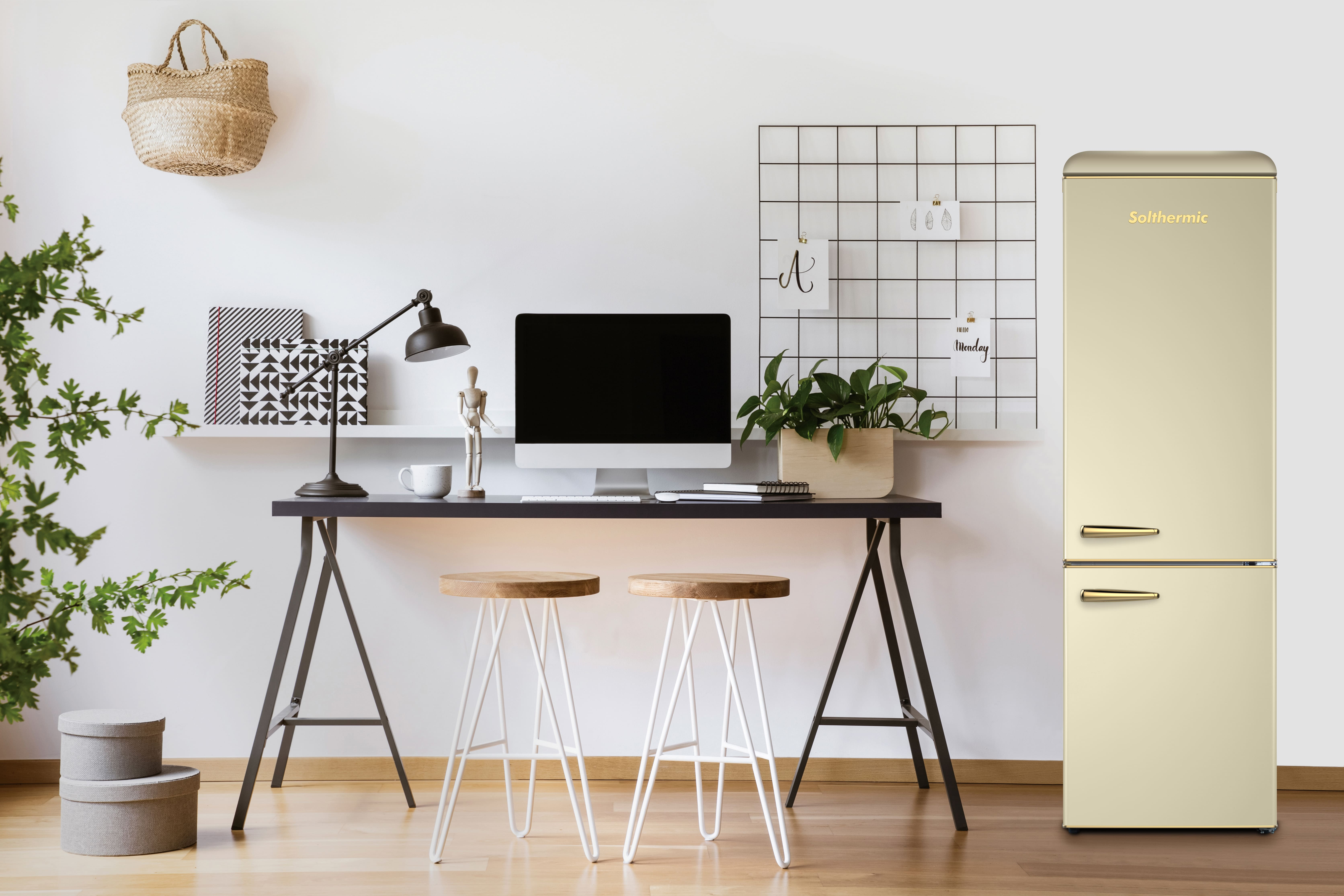 Un refrigerador color crema junto a un escritorio con computadora, taburetes y plantas.