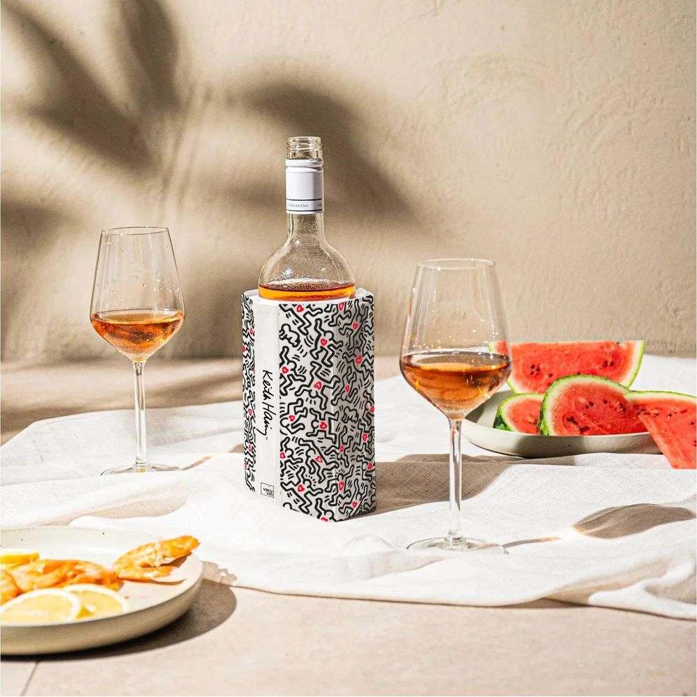 Una bottiglia di vino in un refrigeratore Keith Haring tra due bicchieri di vino rosato, con fette di anguria nelle vicinanze.