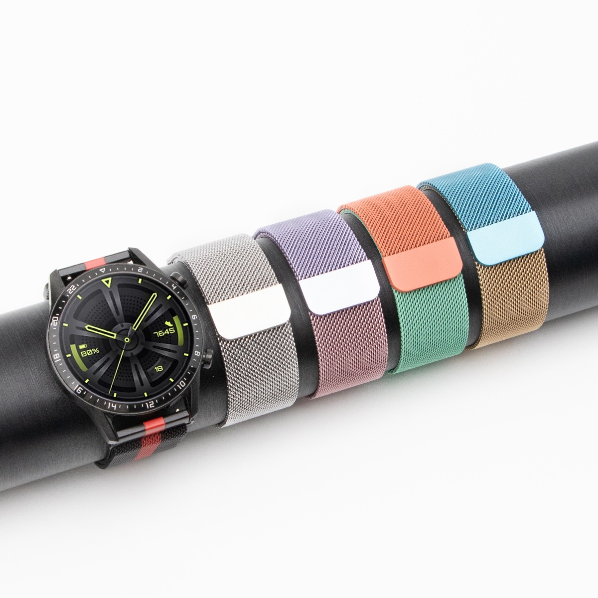 Uno smartwatch nero con cinturini colorati appoggiati su un cilindro nero.
