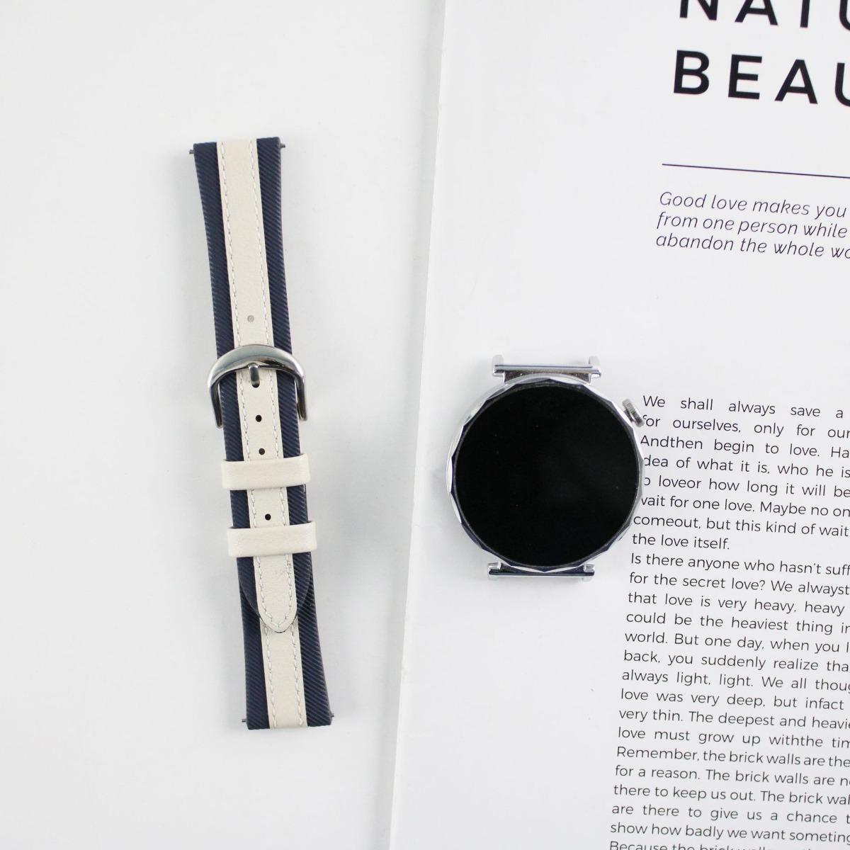Ein gestreiftes Armband und eine Uhr liegen auf bedrucktem Papier.