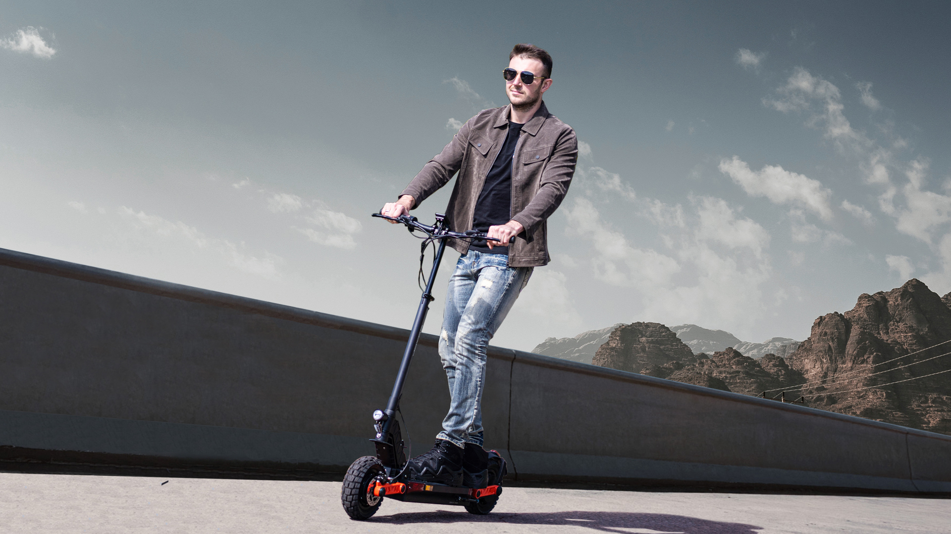 Ein Mann fährt einen E-Scooter vor bergiger Kulisse.