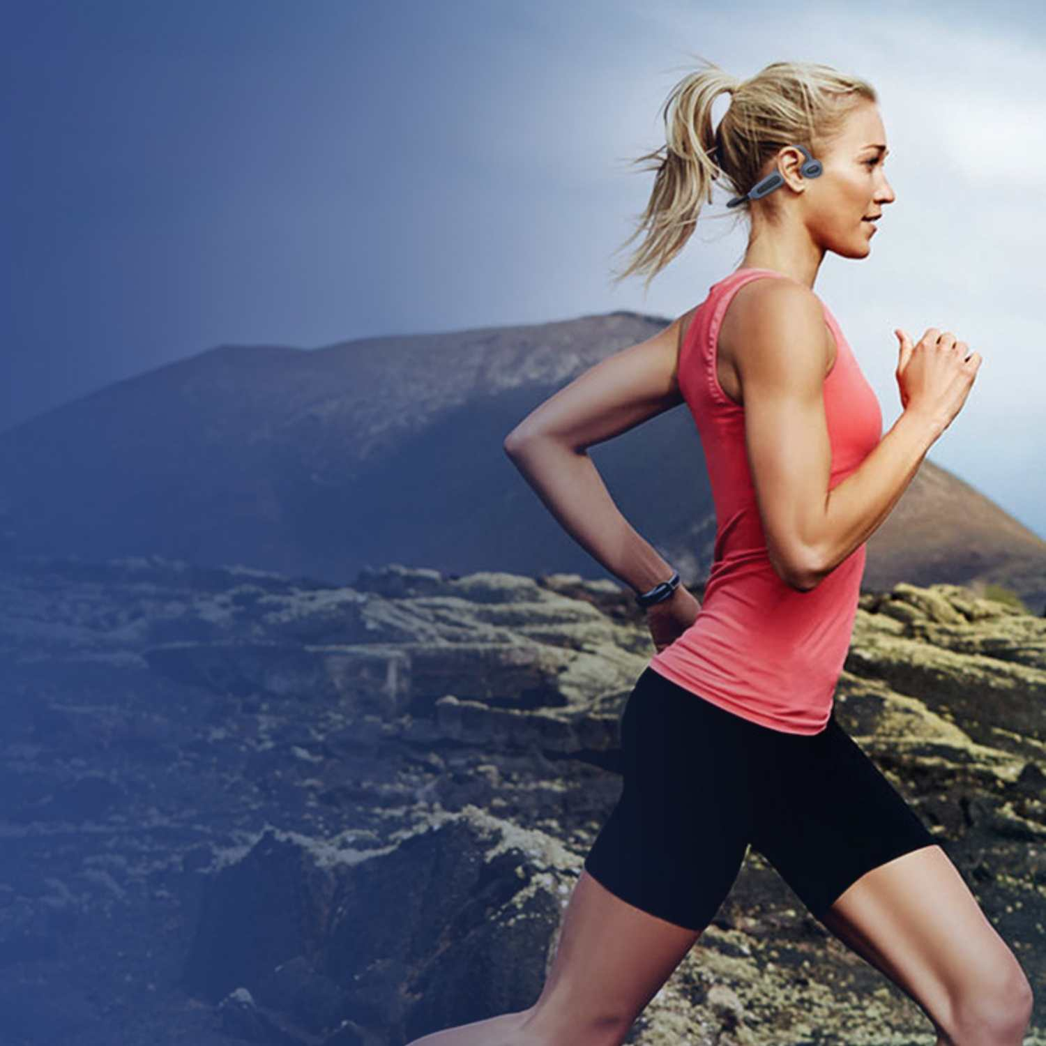 Eine Frau mit blondem Pferdeschwanz joggt in der Natur mit Kopfhörern.