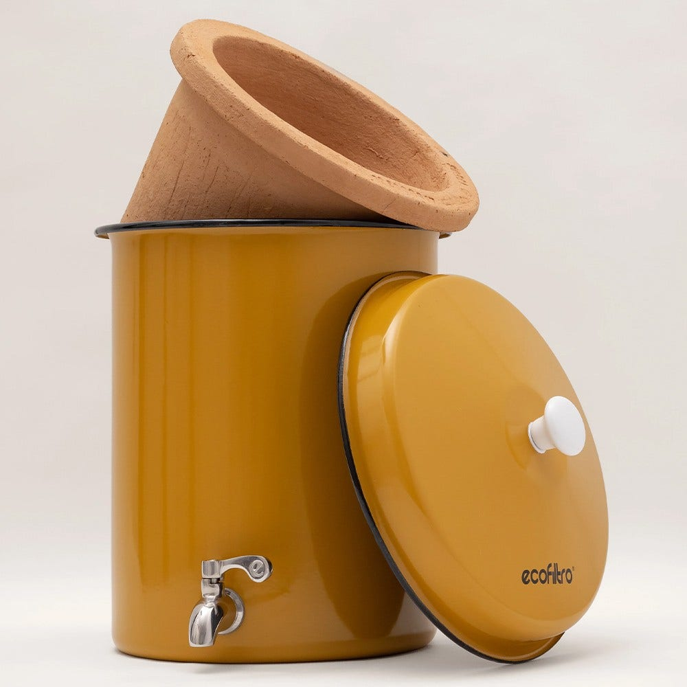 Un contenitore per filtro dell'acqua giallo senape con filtro in terracotta e rubinetto argentato.