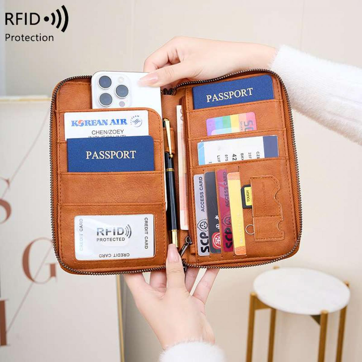Eine braune Leder-Reisetasche mit Pässen, Karten, Telefon und Stift.