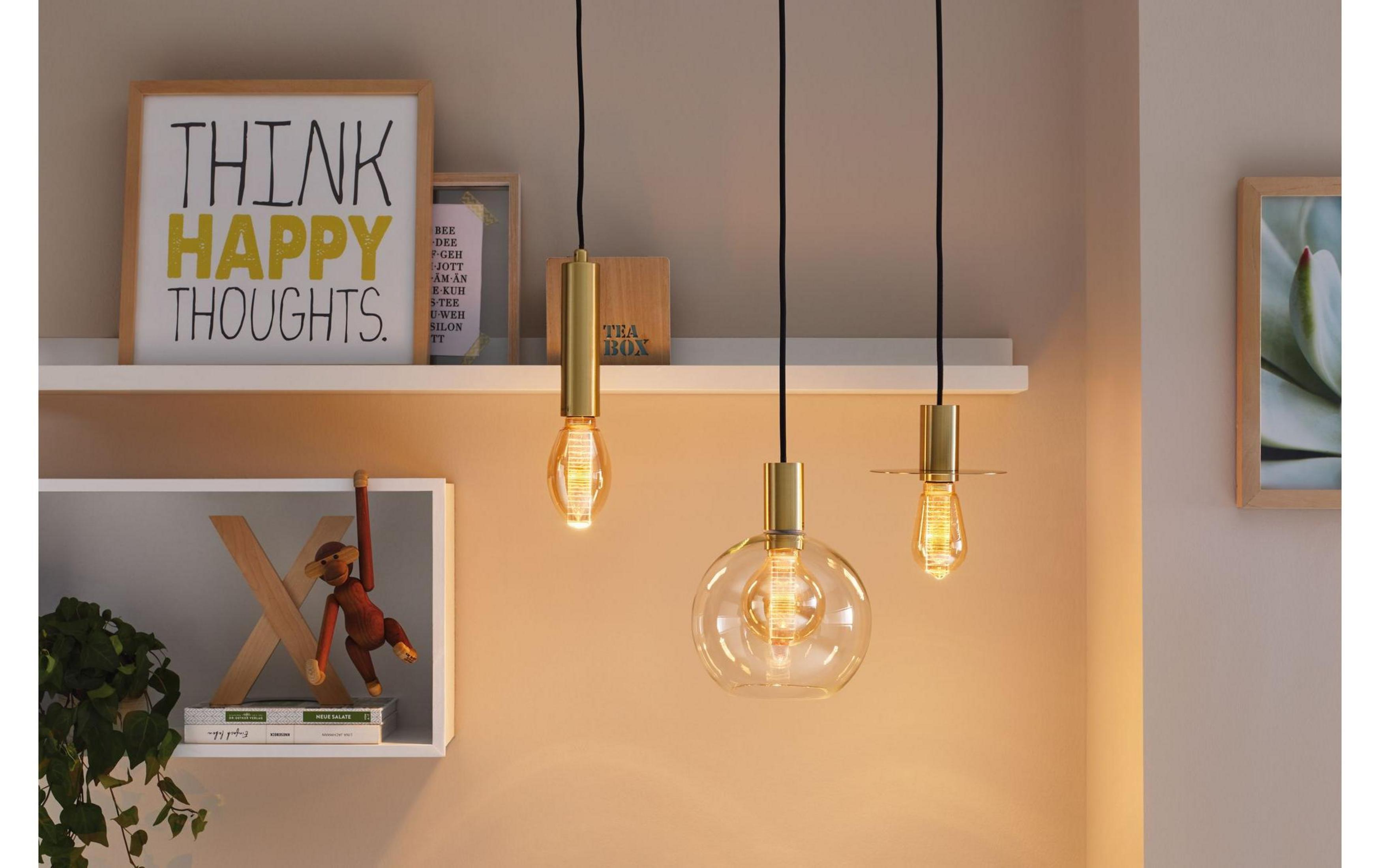 Trzy złote lampy wiszące nad półką z dekoracjami.