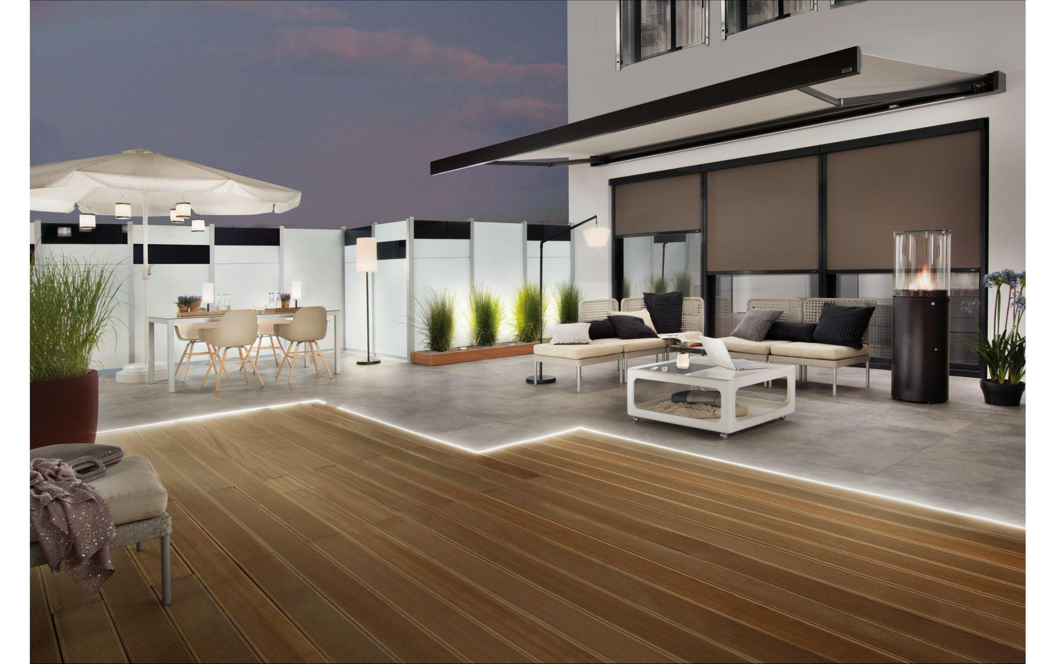 Nowoczesne patio z jadalnią, częścią wypoczynkową i podgrzewaczem tarasowym o zmierzchu.