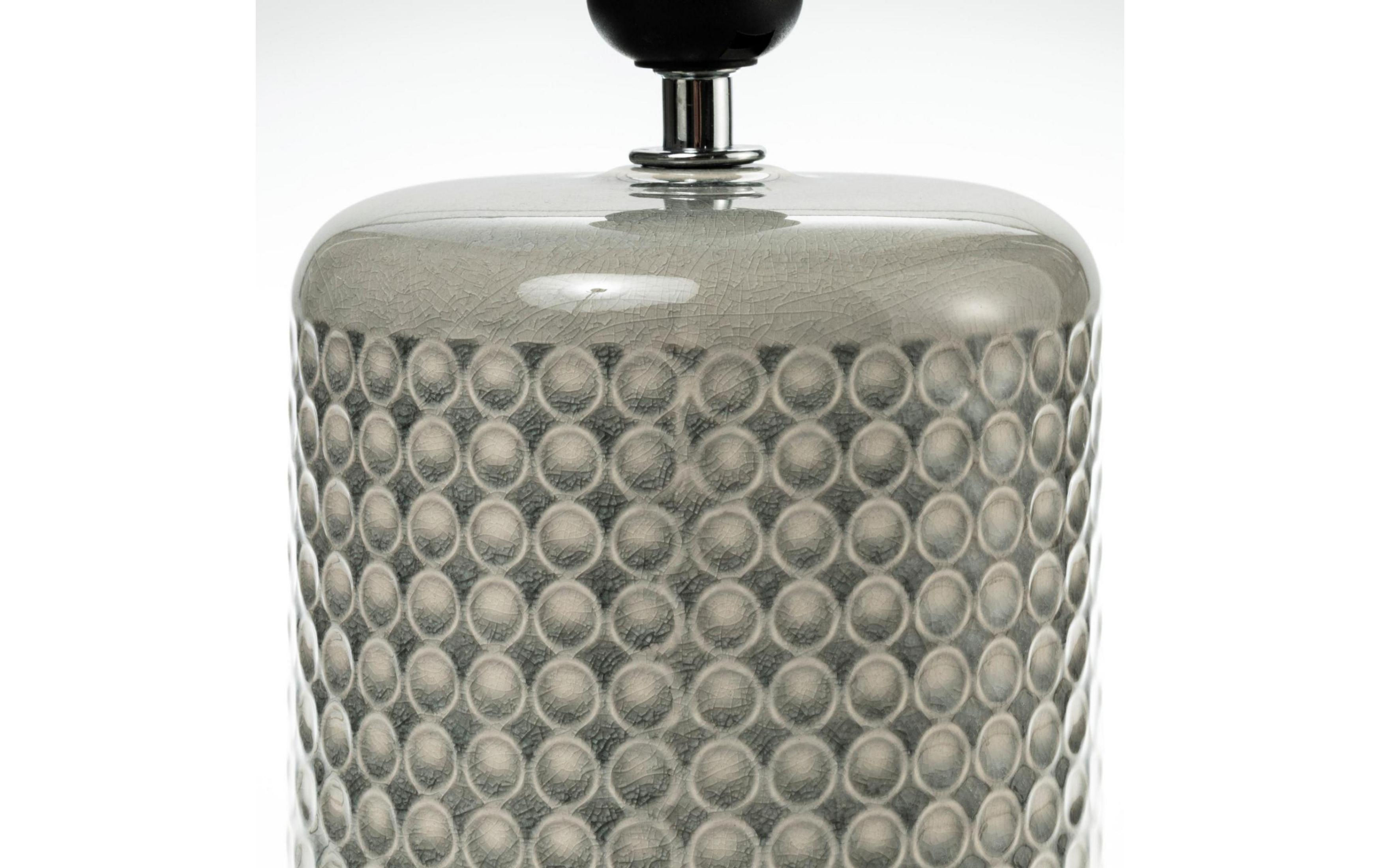 Szara lampa z wzorem kół i pęknięciami na błyszczącym wykończeniu.