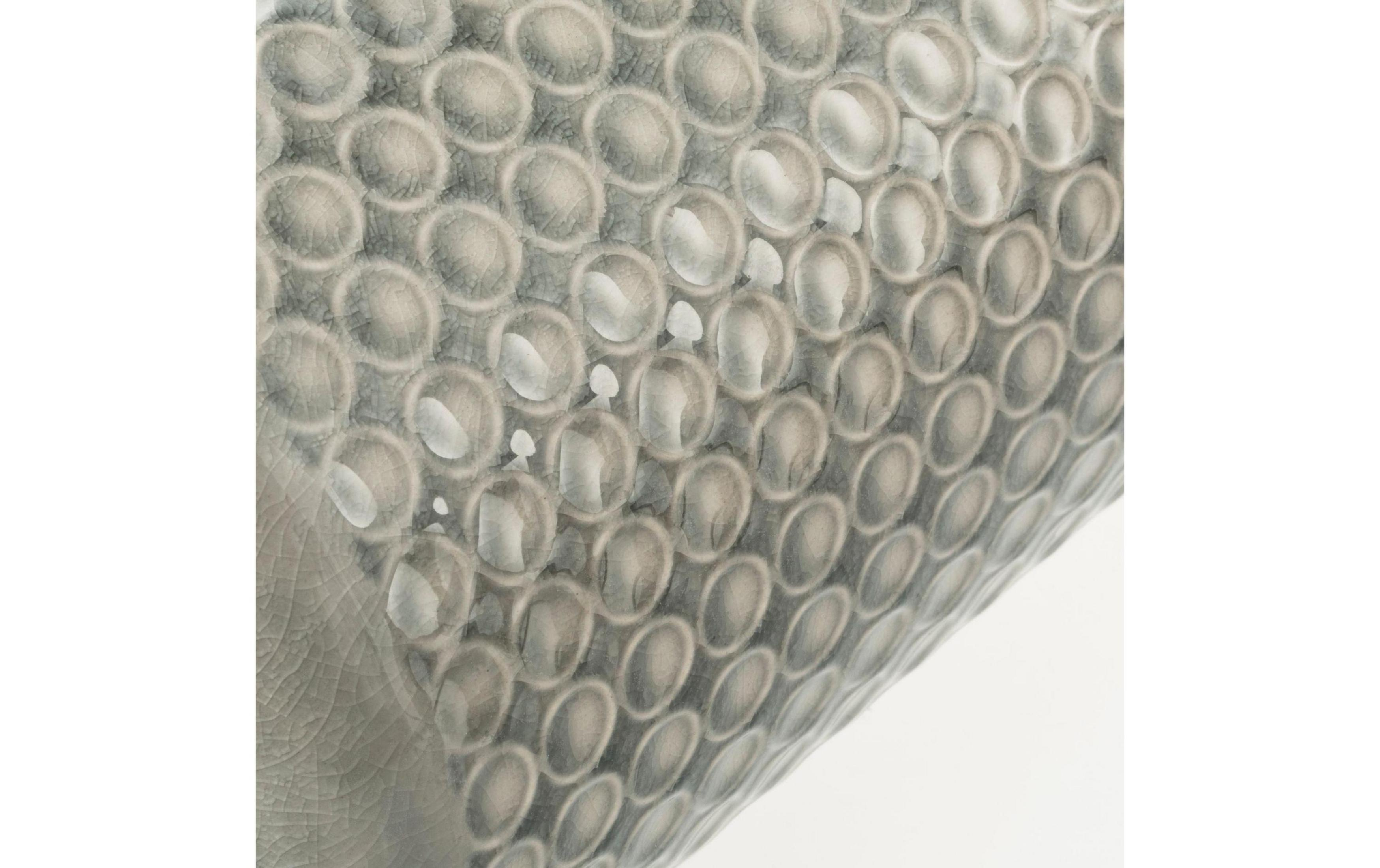 Szara ceramika z okrągłym wzorem i pęknięciami.