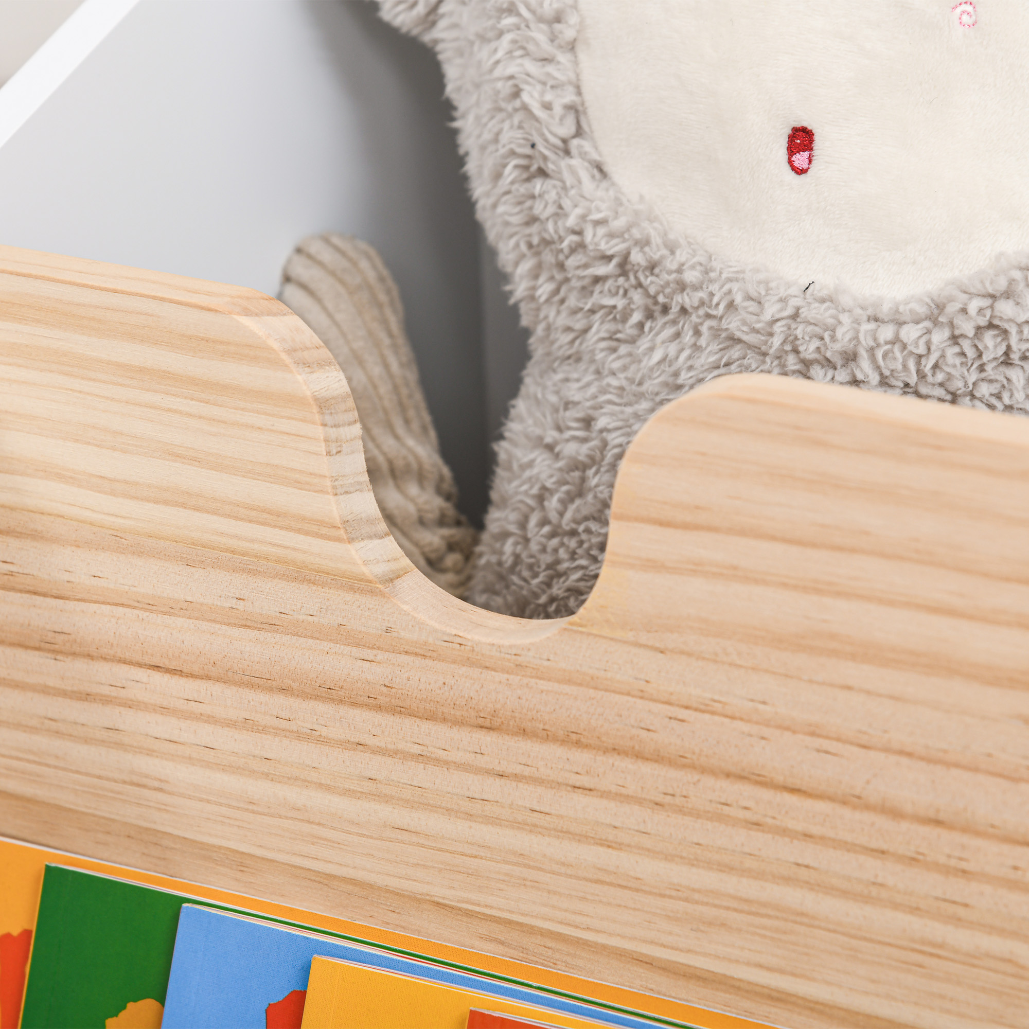Estante de madera con peluche y libros. Primer plano.