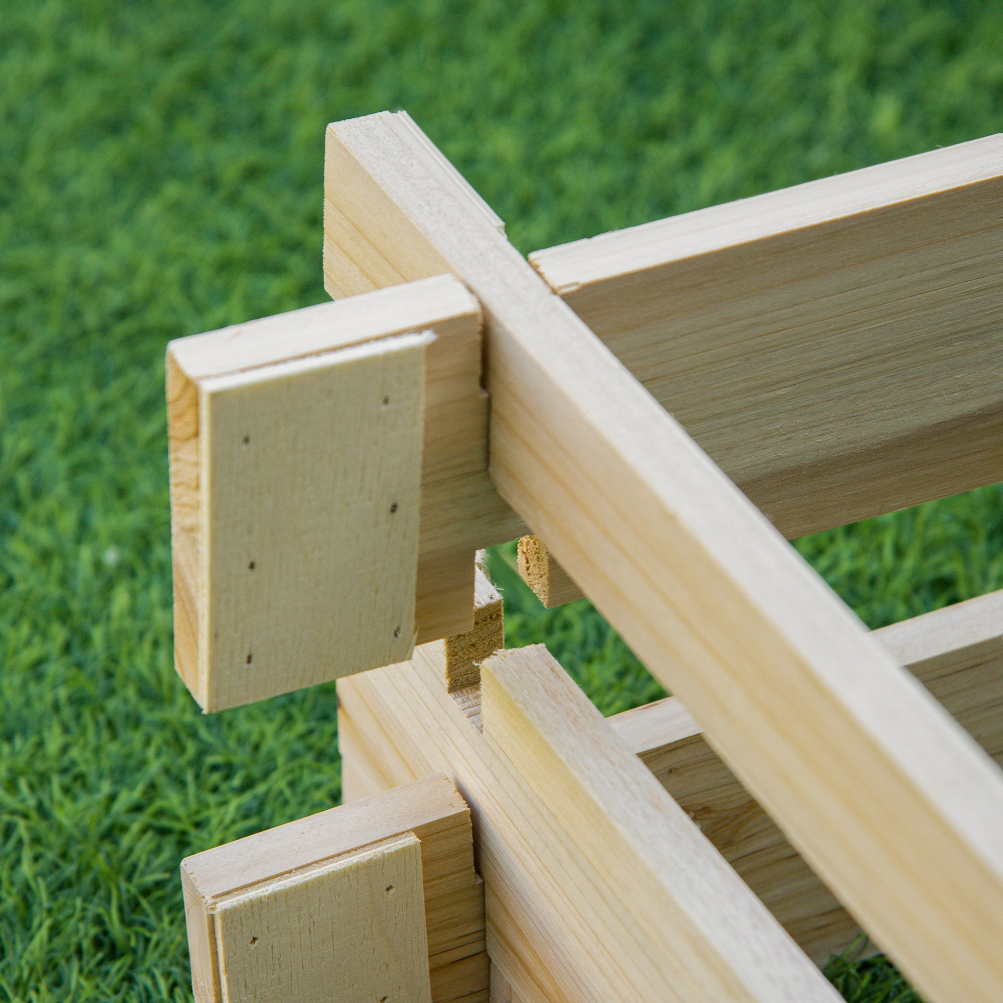 Estructura de madera sobre hierba verde, primer plano de las uniones.