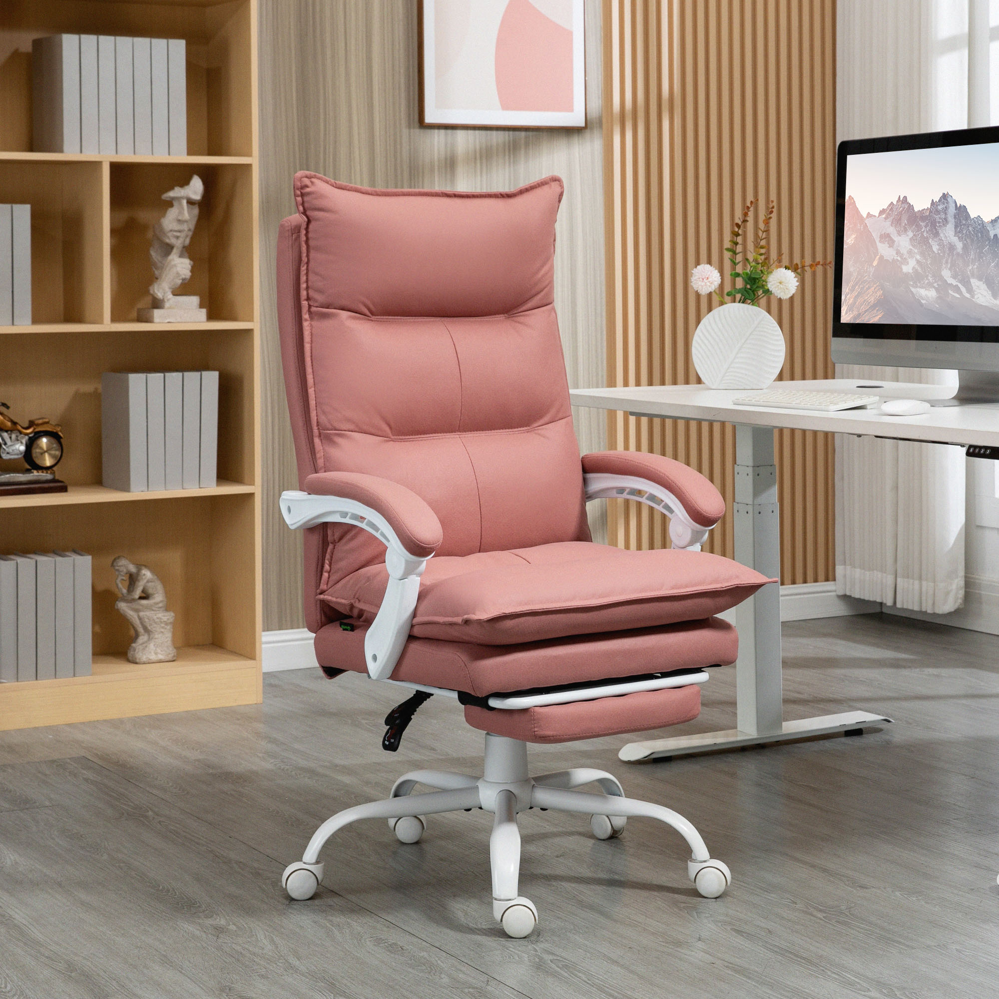 Una silla de oficina rosa con reposapiés está junto a un escritorio con ordenador.
