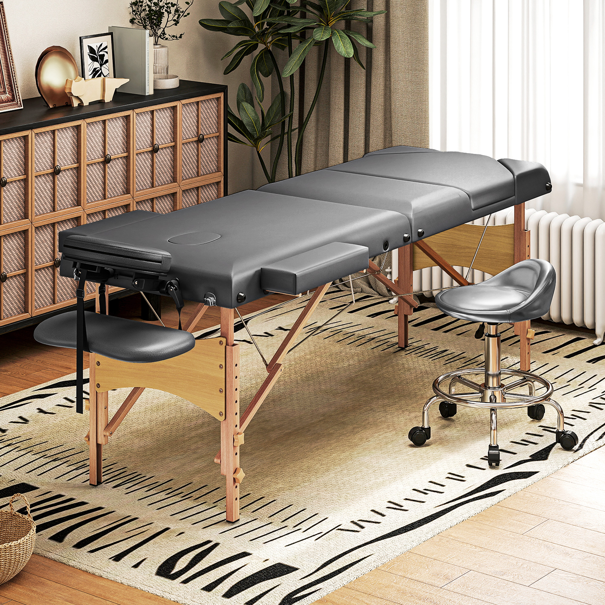 Una camilla de masaje gris con marco de madera y taburete ajustable.