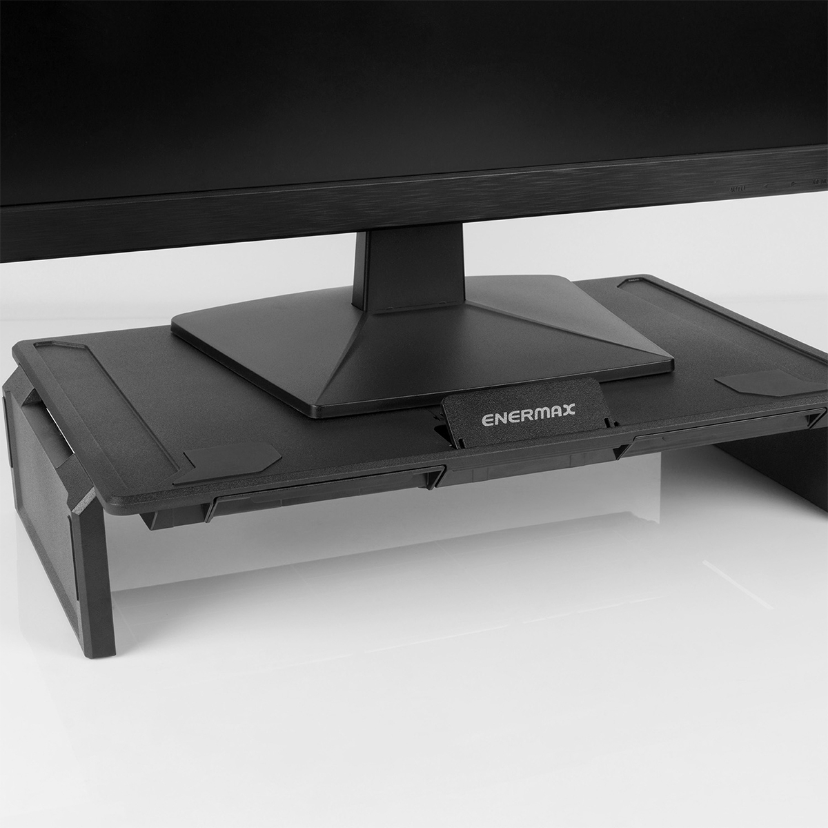 Siyah bir monitör, ENERMAX logolu siyah yükseltici stand üzerinde duruyor.