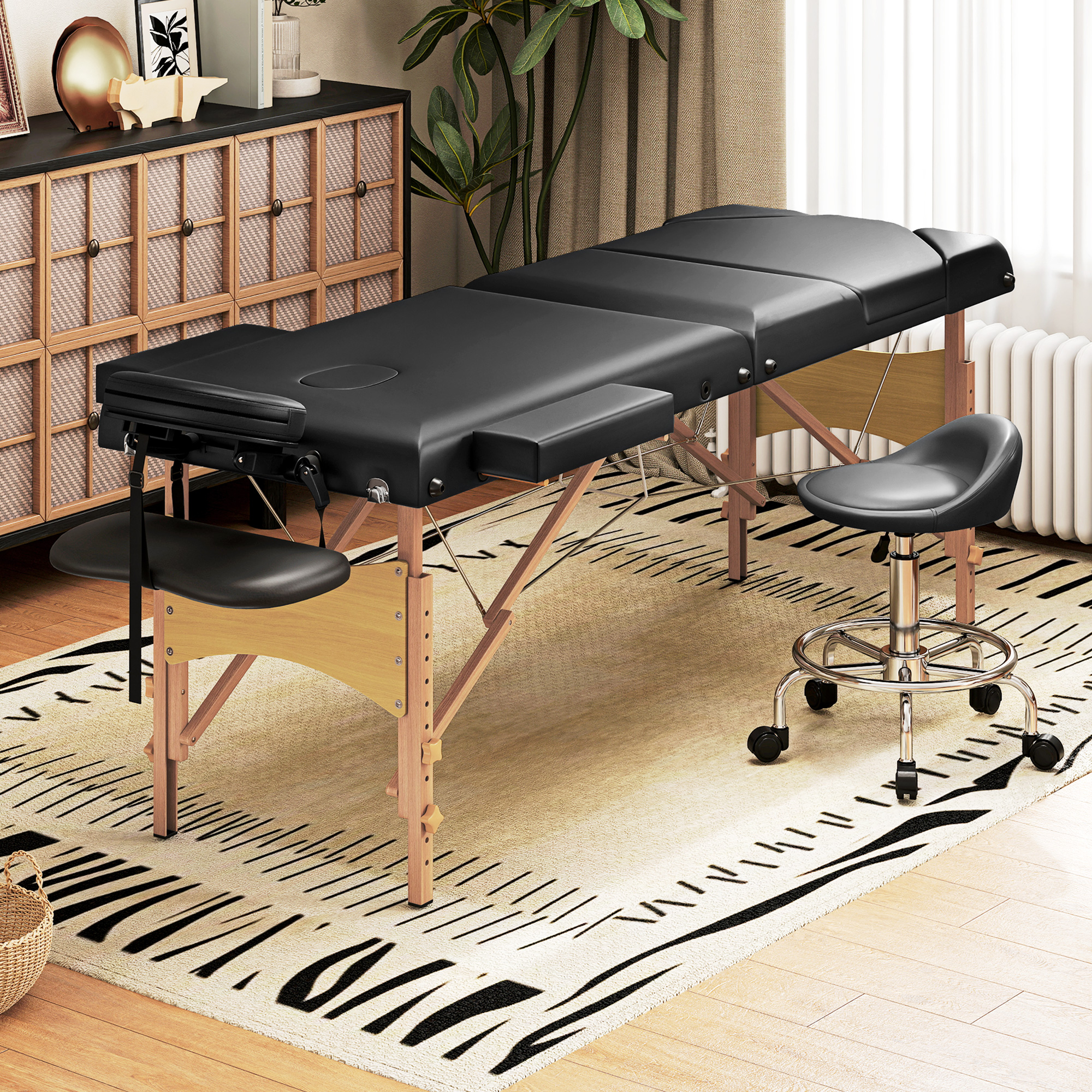 Mesa de masaje negra con marco de madera y taburete sobre alfombra.