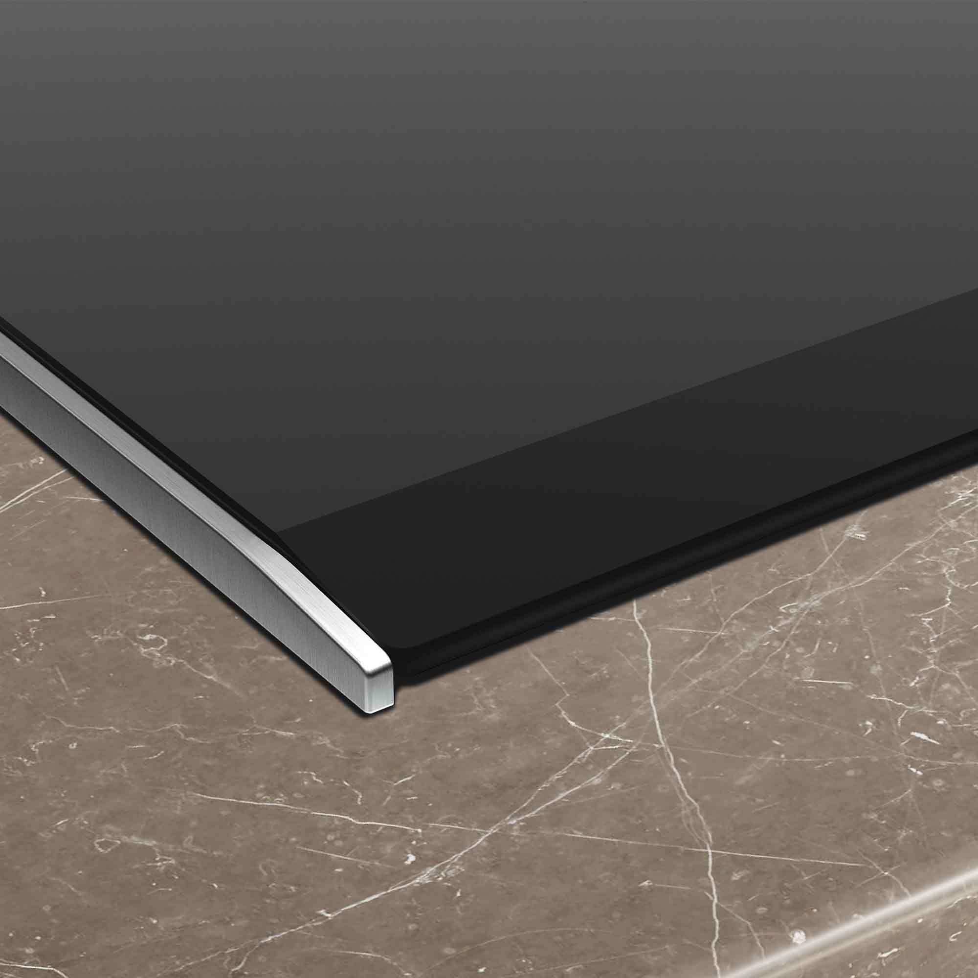 Zbliżenie gładkiej czarnej powierzchni z srebrną krawędzią na marmurze.