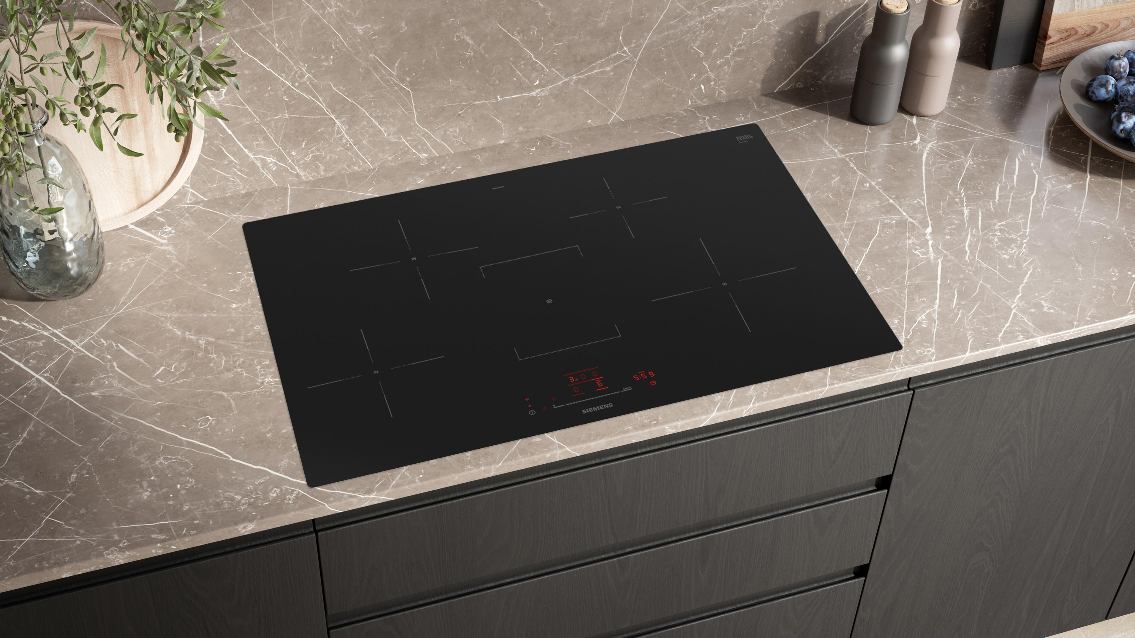 Une plaque à induction noire sur un plan de travail en marbre avec des décorations.