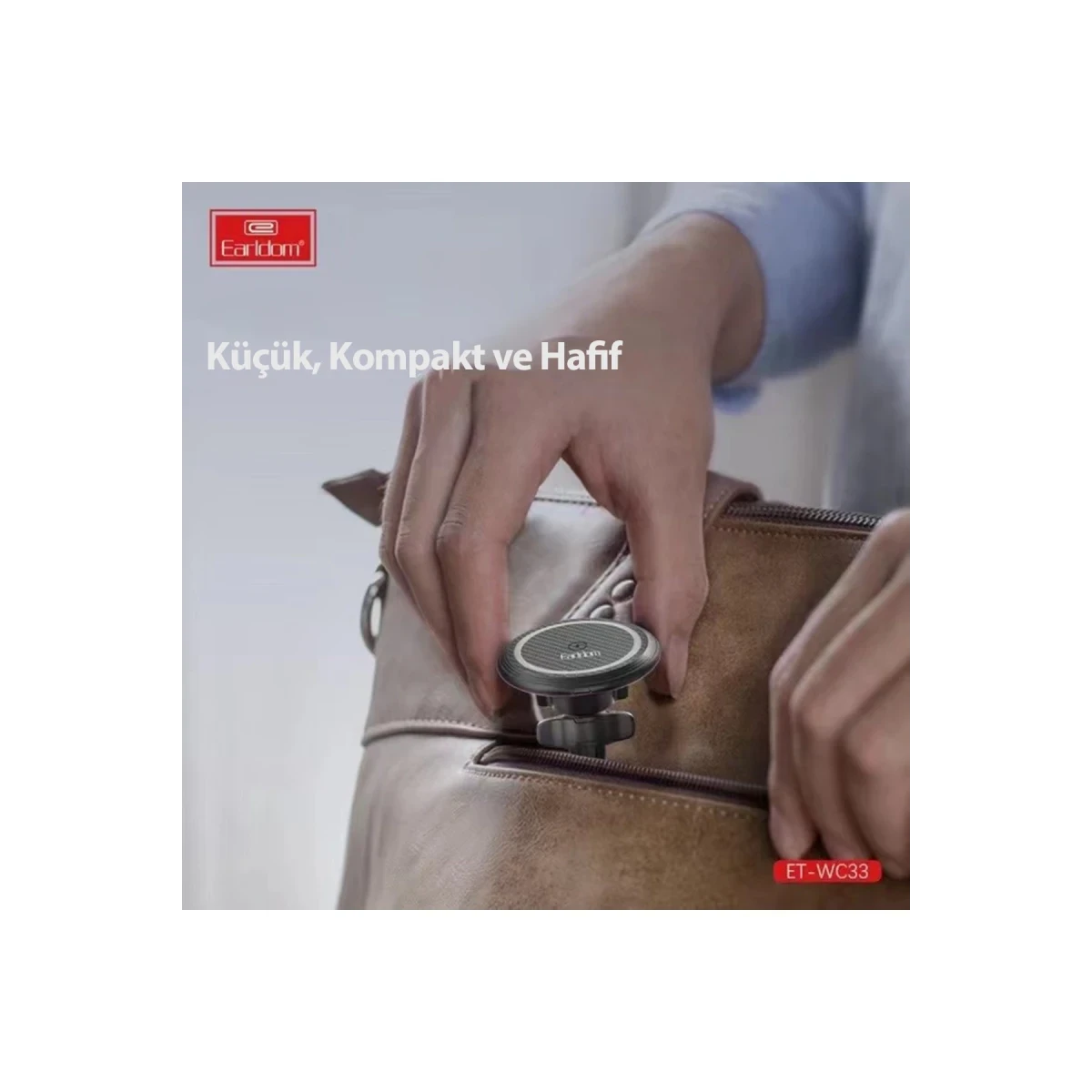Bir el, kahverengi deri çantaya küçük siyah bir araç tutucu yerleştiriyor.