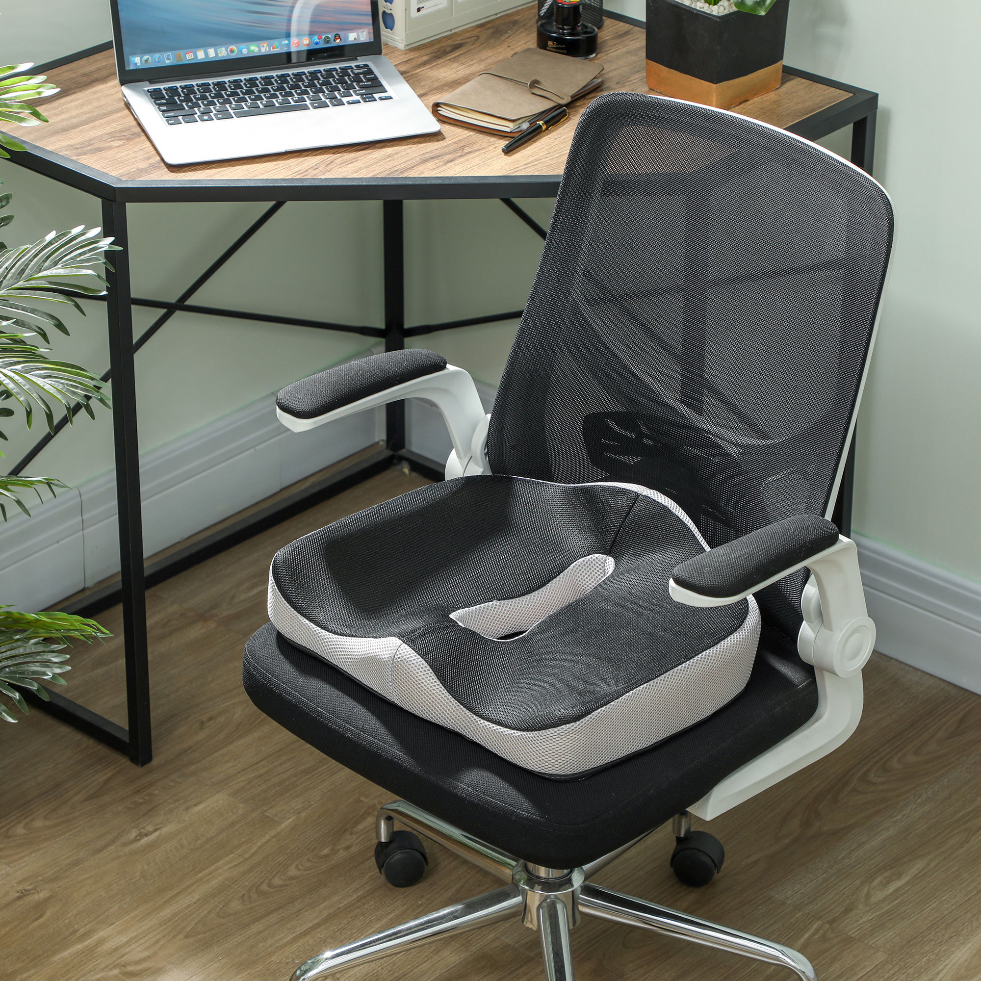 Una silla de oficina negra con cojín negro y gris está sobre un suelo de madera.