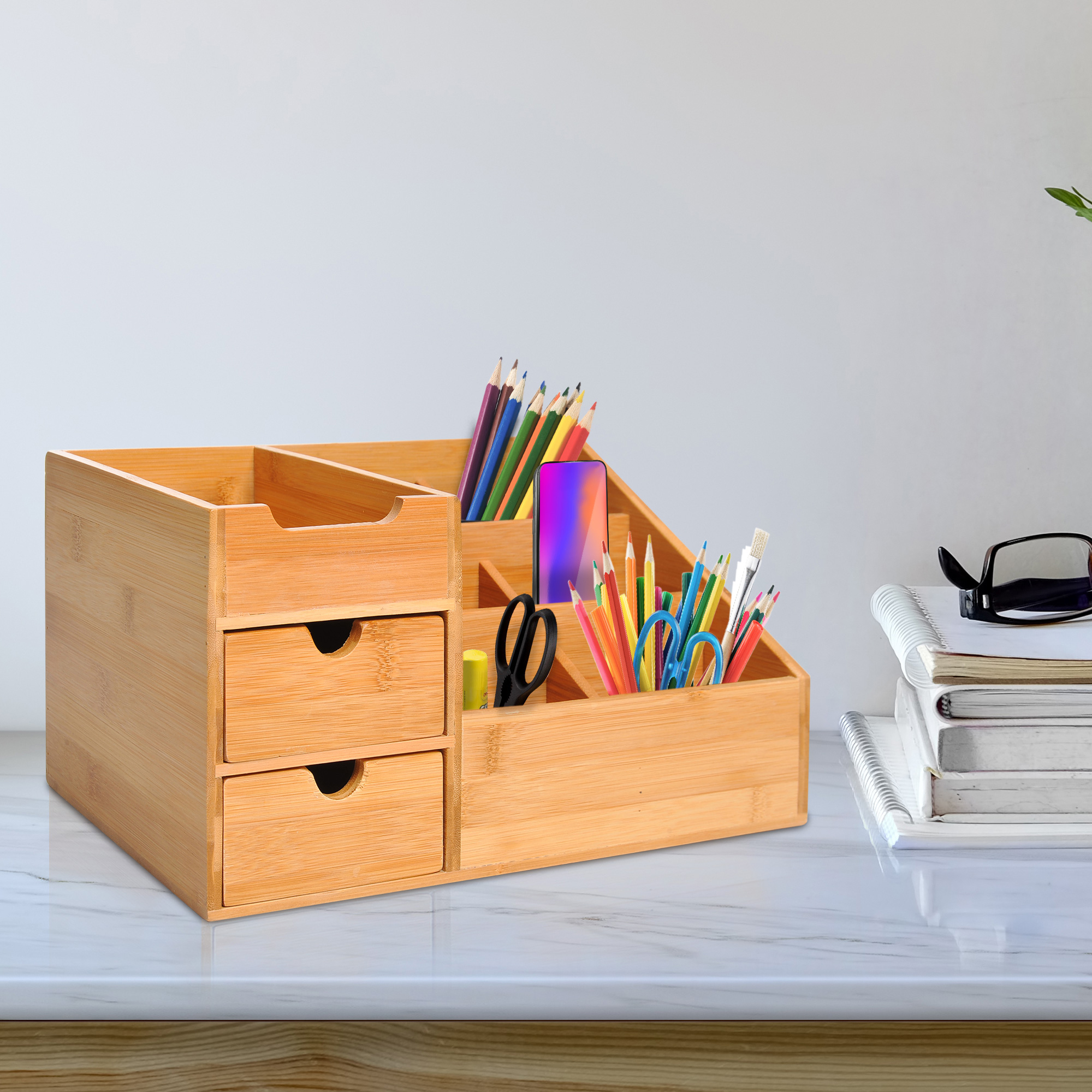 Un organizador de escritorio de madera con cajones, bolígrafos, tijeras y un teléfono.
