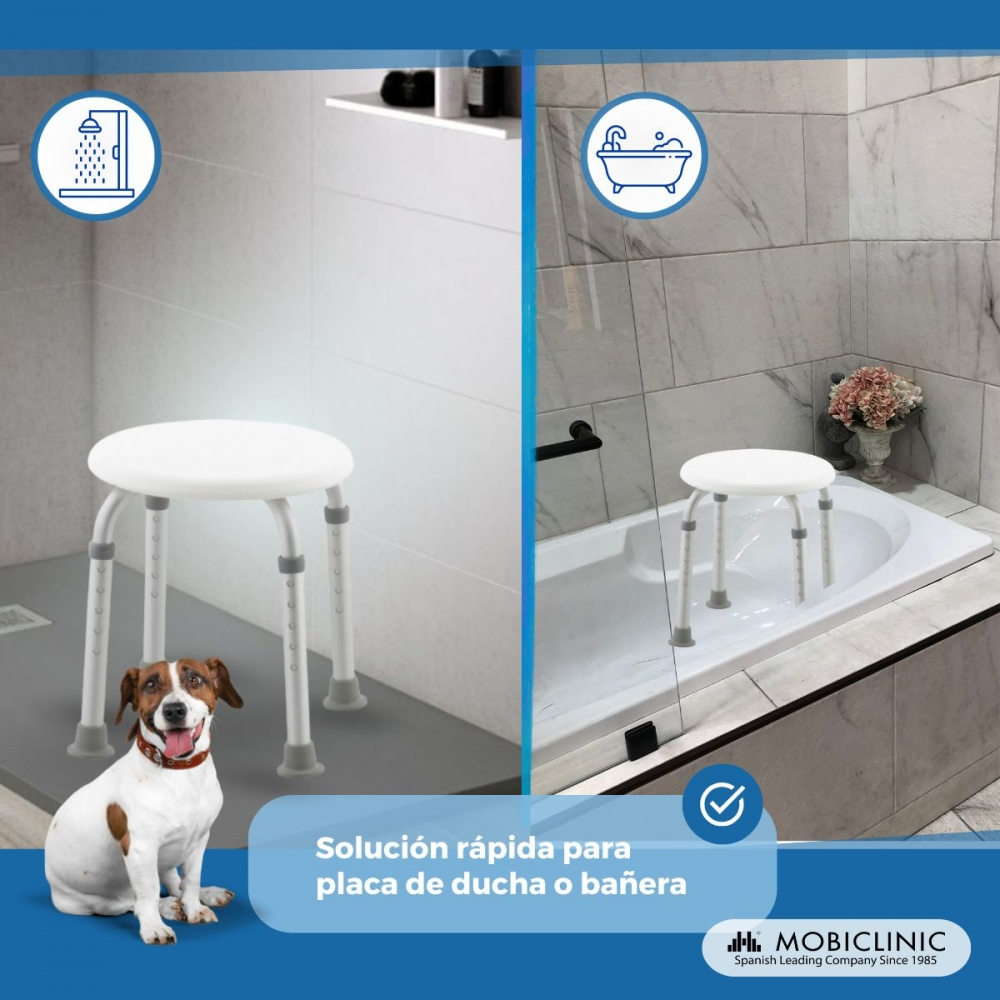 Un taburete blanco de ducha está en una ducha y una bañera. Un perro se sienta delante.
