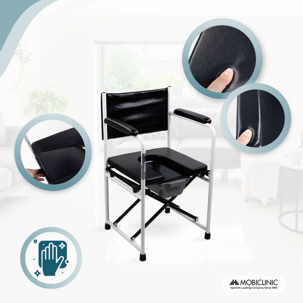 Una silla inodoro plegable negra con marco blanco está en una habitación luminosa.