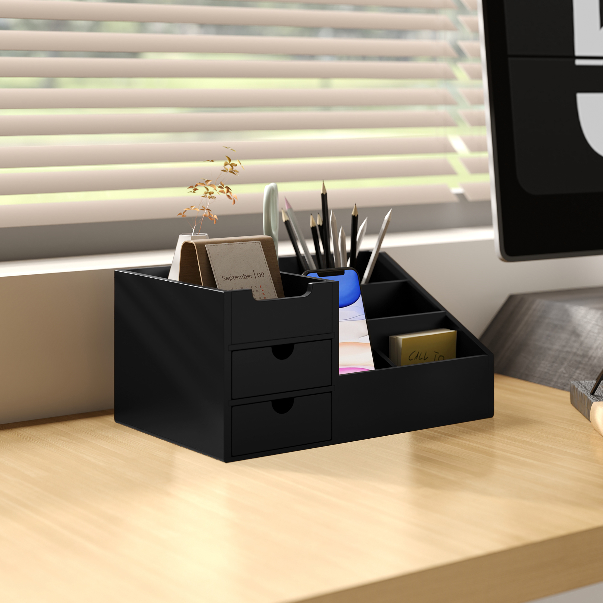 Un organizador de escritorio negro con cajones, bolígrafos, teléfono y calendario.