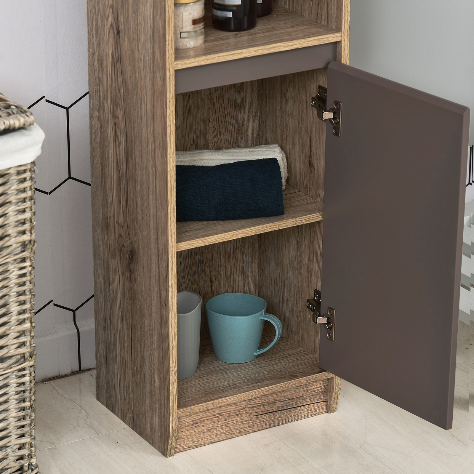 Un mueble de madera con puerta abierta muestra toallas dobladas y dos tazas.