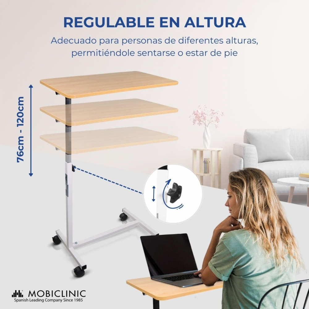 Una mesa regulable en altura con portátil y una mujer sentada frente a ella.