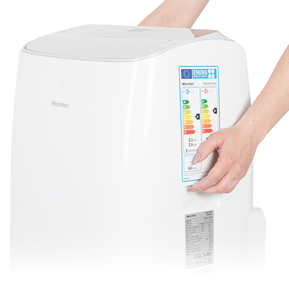 Dłonie trzymają biały klimatyzator z etykietą energetyczną i danymi technicznymi.
