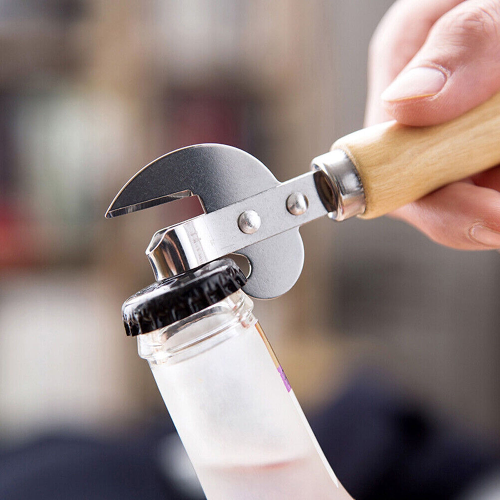 Eine Hand benutzt einen Flaschenöffner mit Holzgriff, um eine schwarze Kappe von einer Glasflasche zu öffnen.