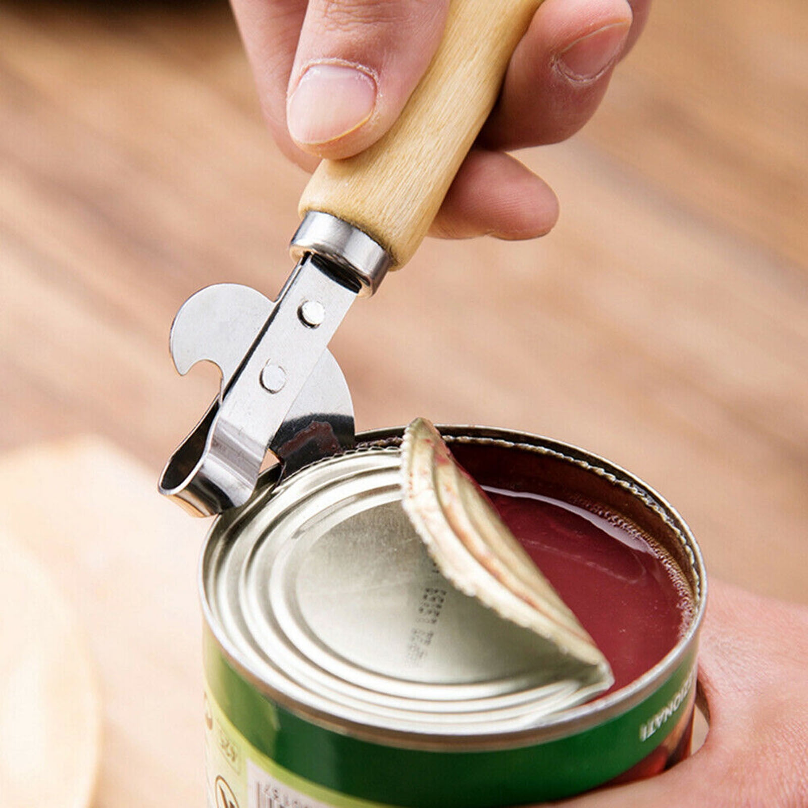 Eine Hand öffnet eine grüne Konserve mit einem Dosenöffner mit Holzgriff.