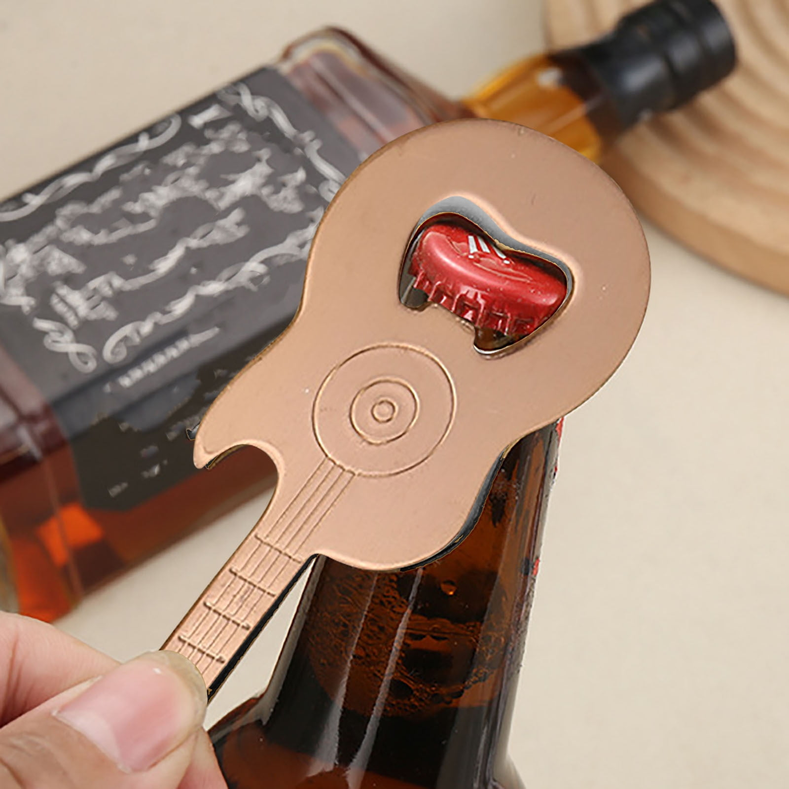 Ein gitarrenförmiger Flaschenöffner öffnet eine rote Kappe auf einer braunen Flasche.