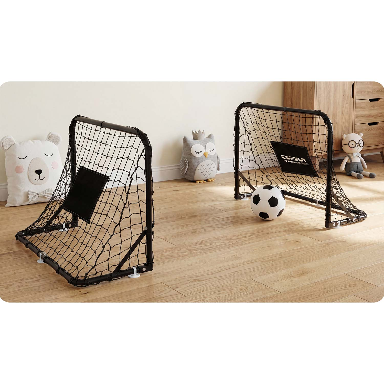 Dwa czarne bramki piłkarskie na drewnianej podłodze. Piłka nożna obok bramki.