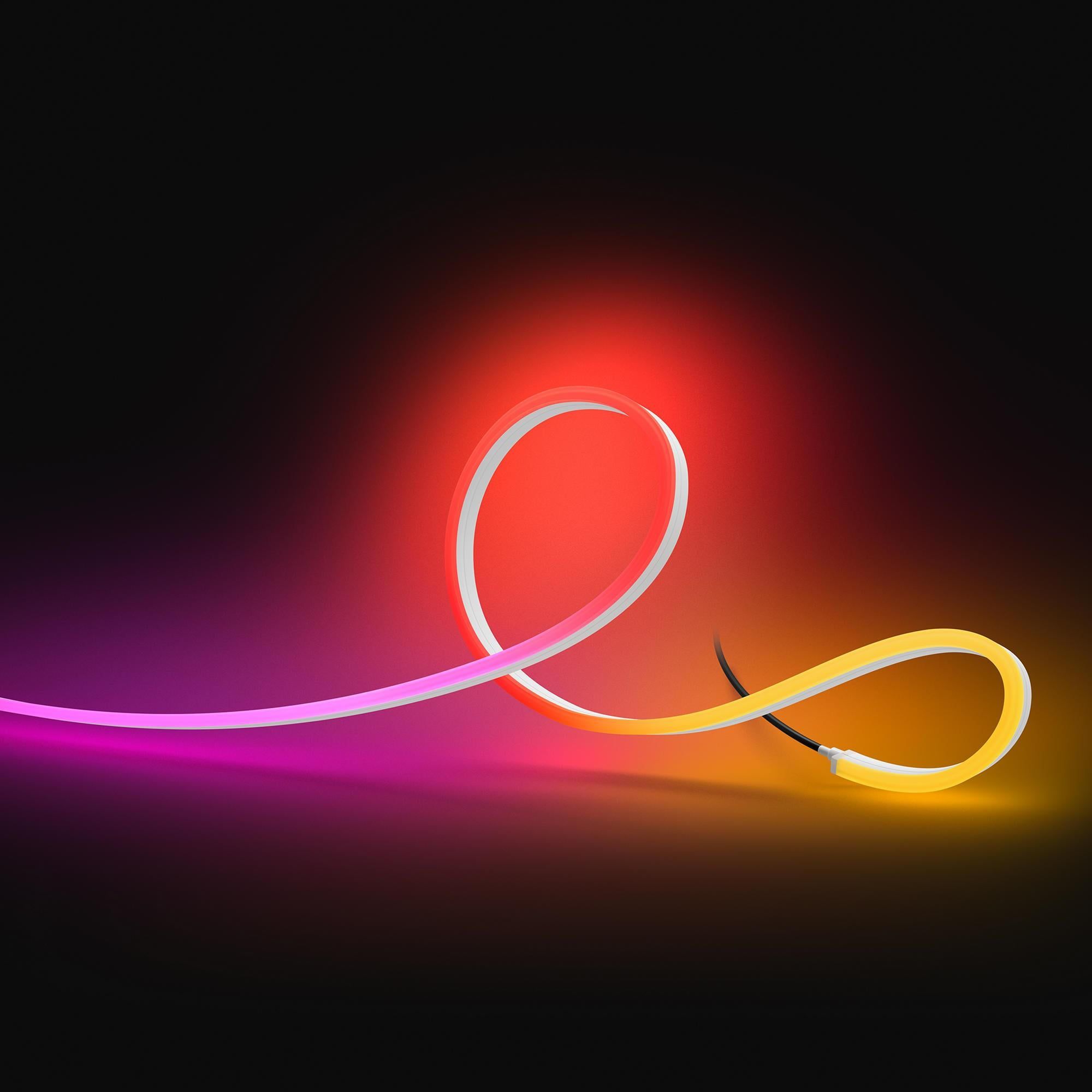 Una striscia flessibile e luminosa rossa, rosa e gialla su sfondo scuro.