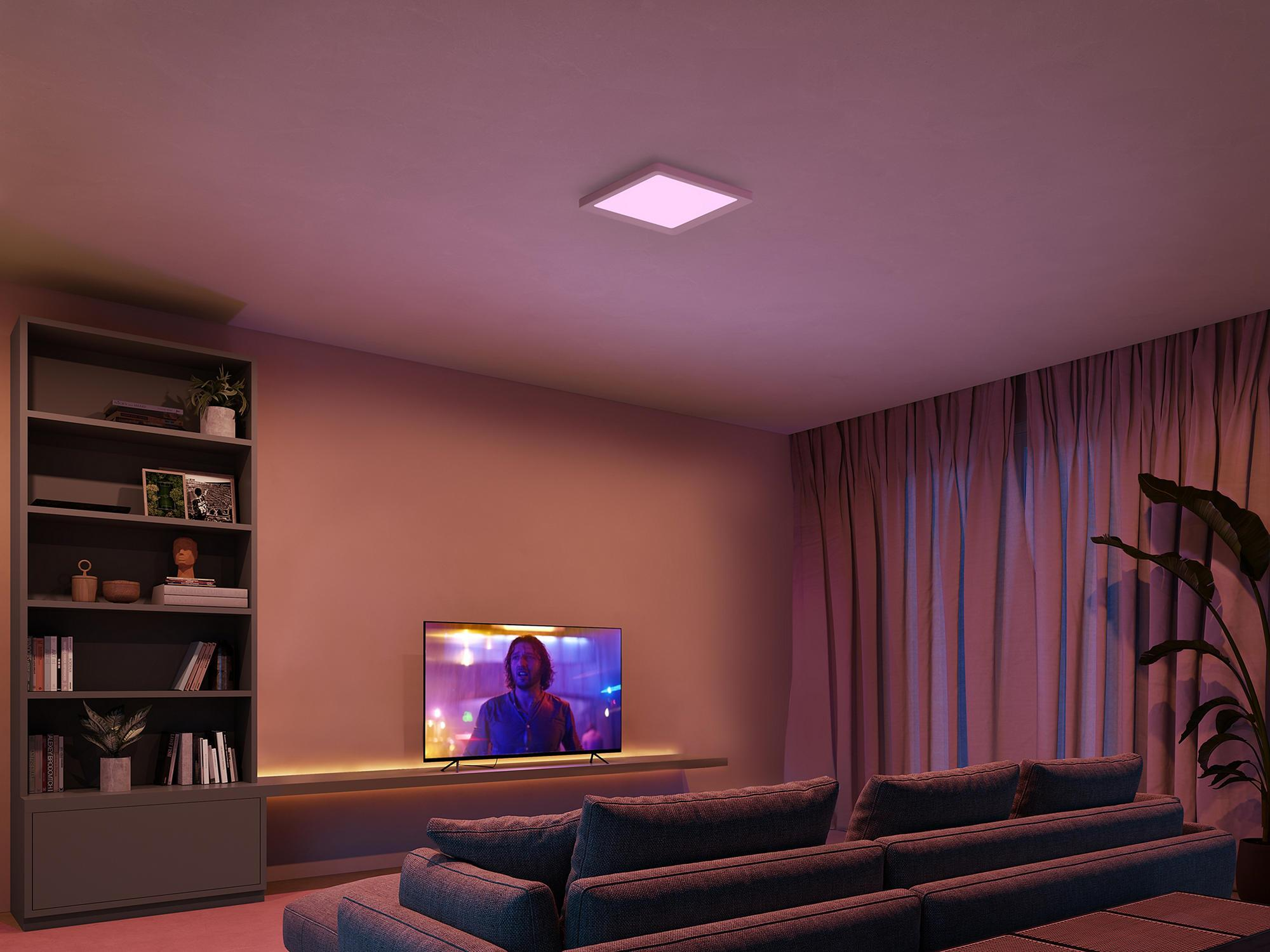 Mor ışıkta kanepe, TV, kitaplık ve tavan lambası bulunan oturma odası.