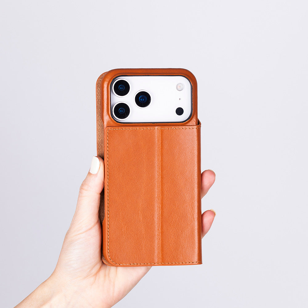 Bir el, içinde beyaz bir telefon bulunan kahverengi deri telefon kılıfını tutuyor.