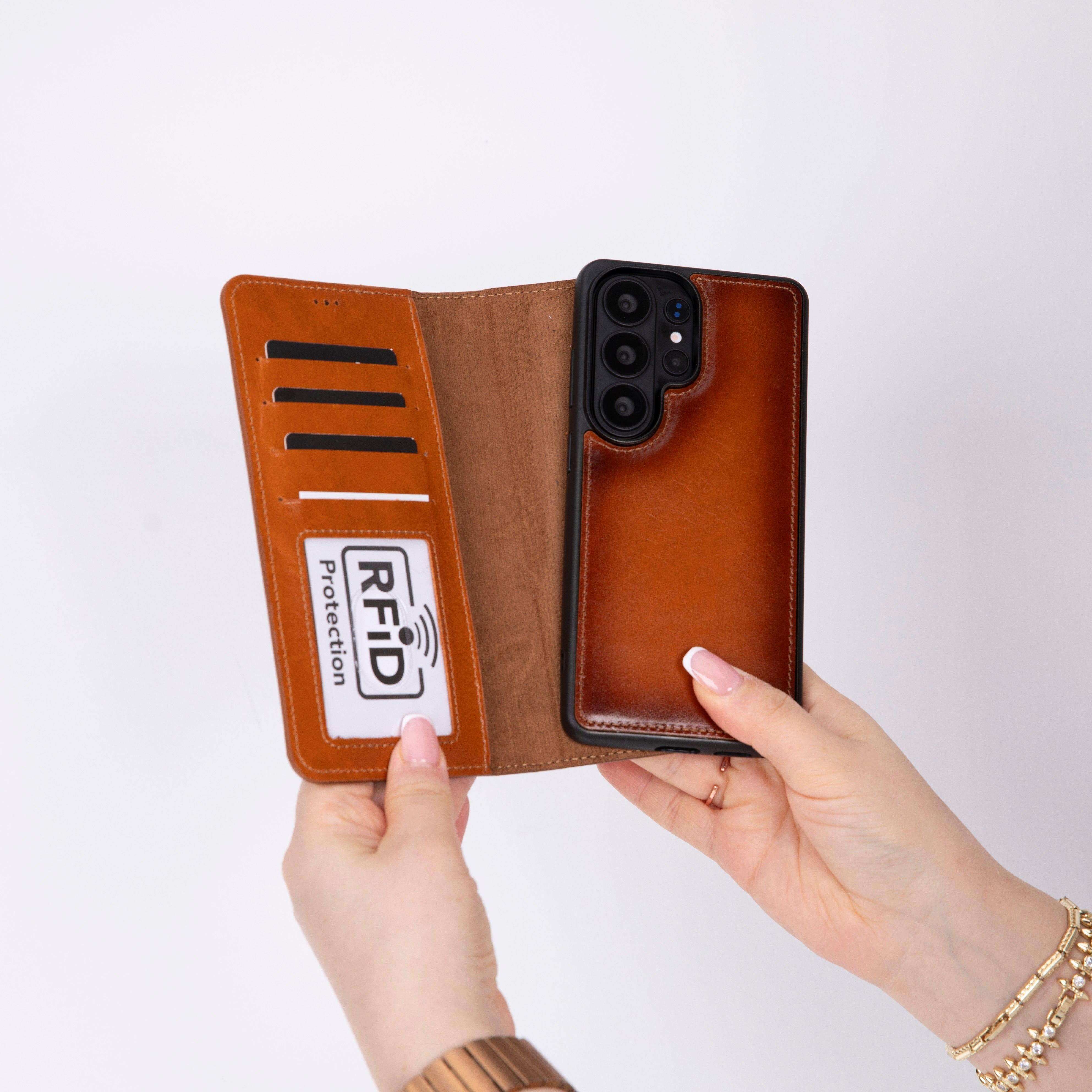 Kart yuvalı ve telefonlu kahverengi deri telefon kılıfı eller tarafından tutuluyor.