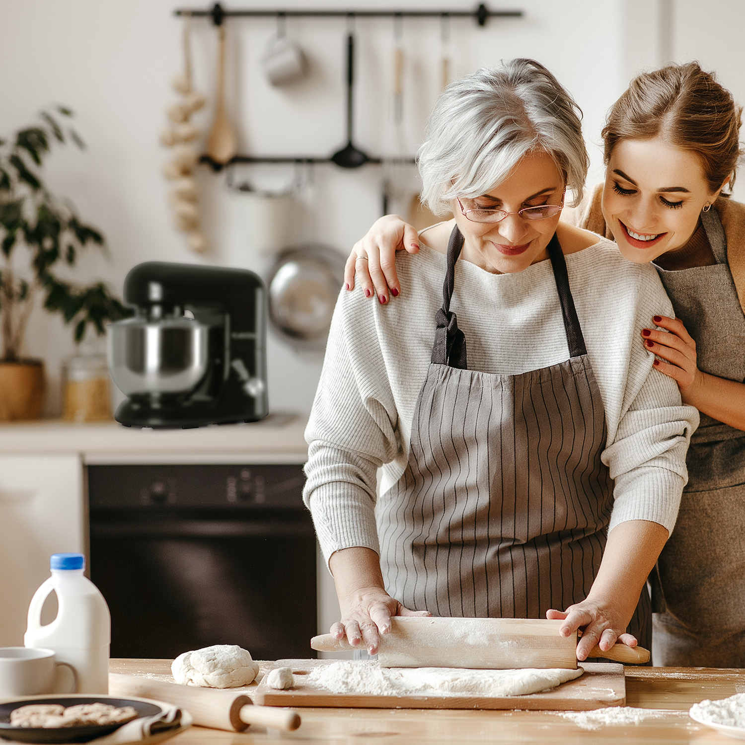 Eine Frau mit grauem Haar und eine jüngere Frau backen mit einem Nudelholz Teig.