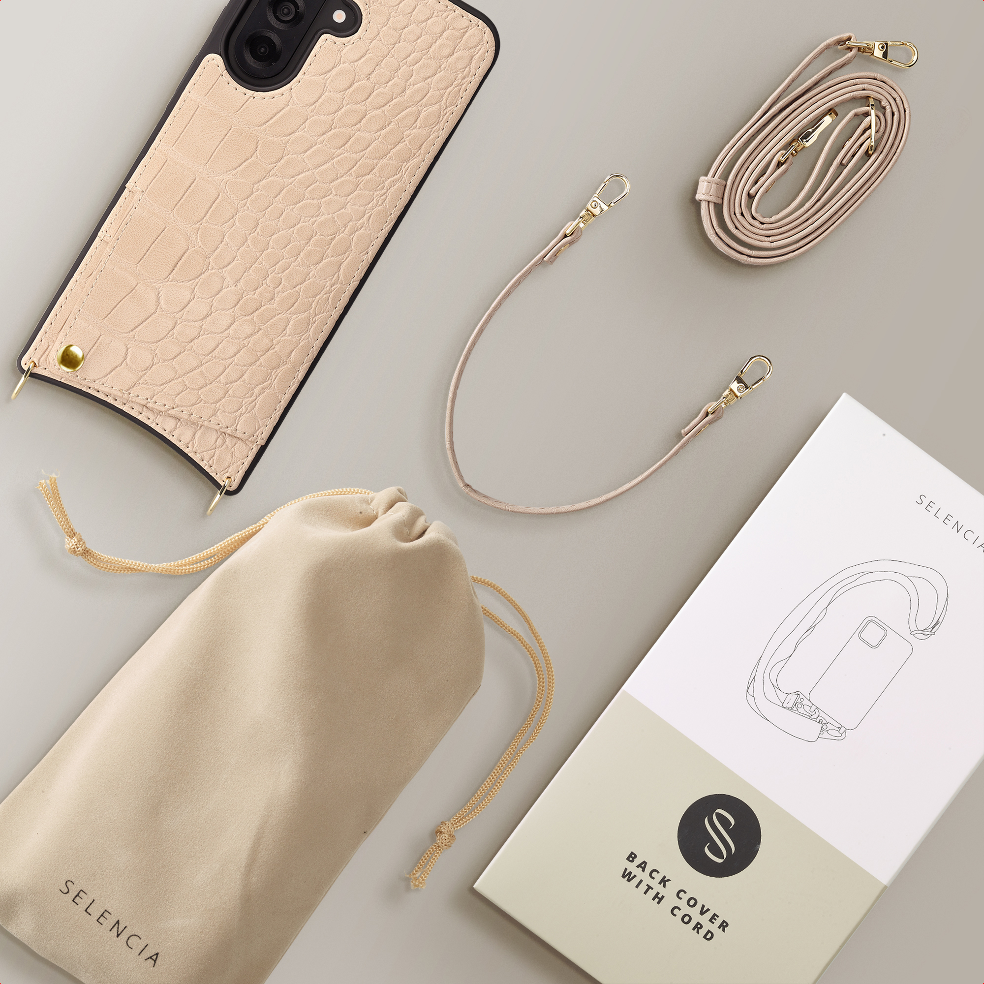 Een lichtbeige krokodillenleren telefoonhoes met koord, buidel en verpakking.