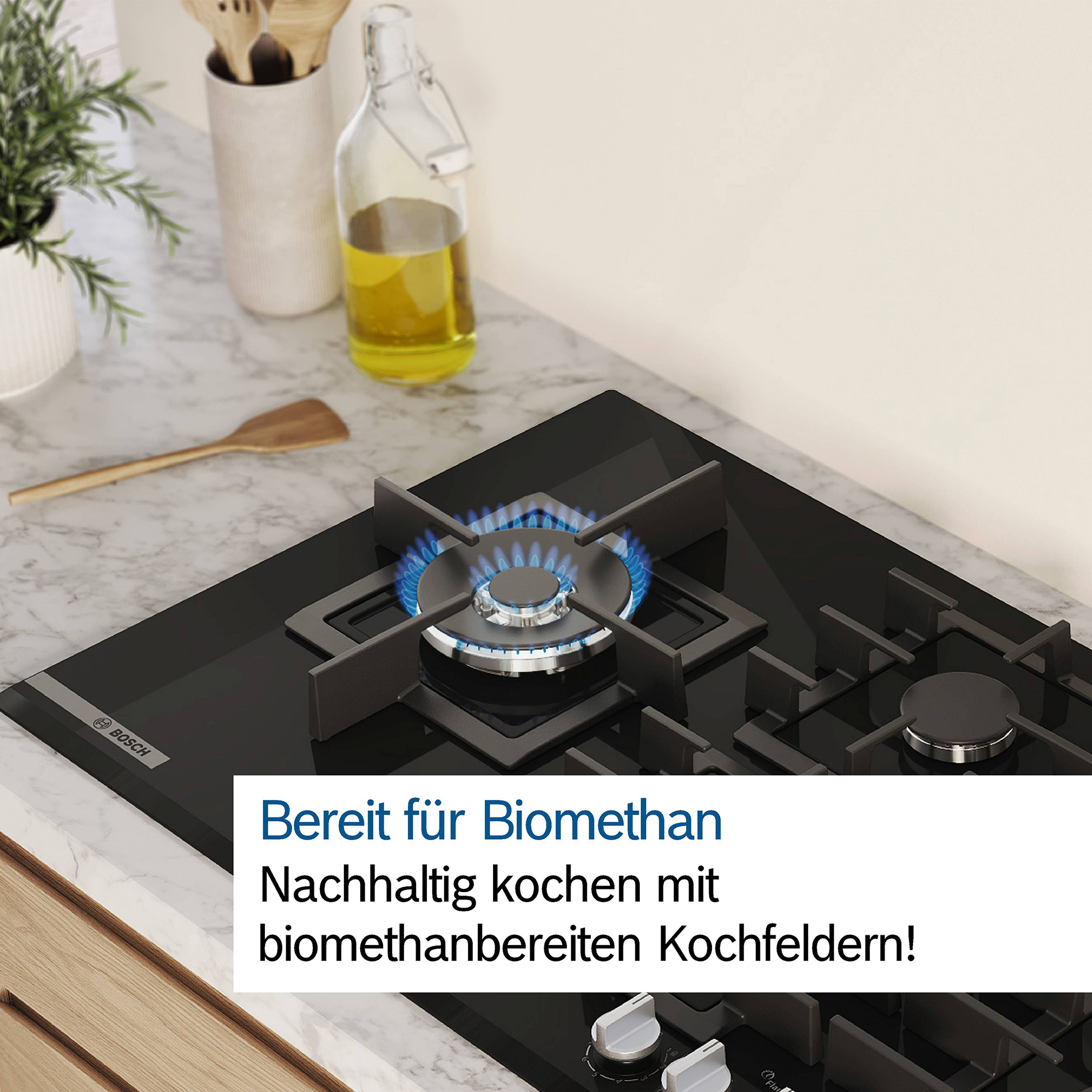 Płyta gazowa Bosch z zapalonym palnikiem. Obok stoi butelka z oliwą.