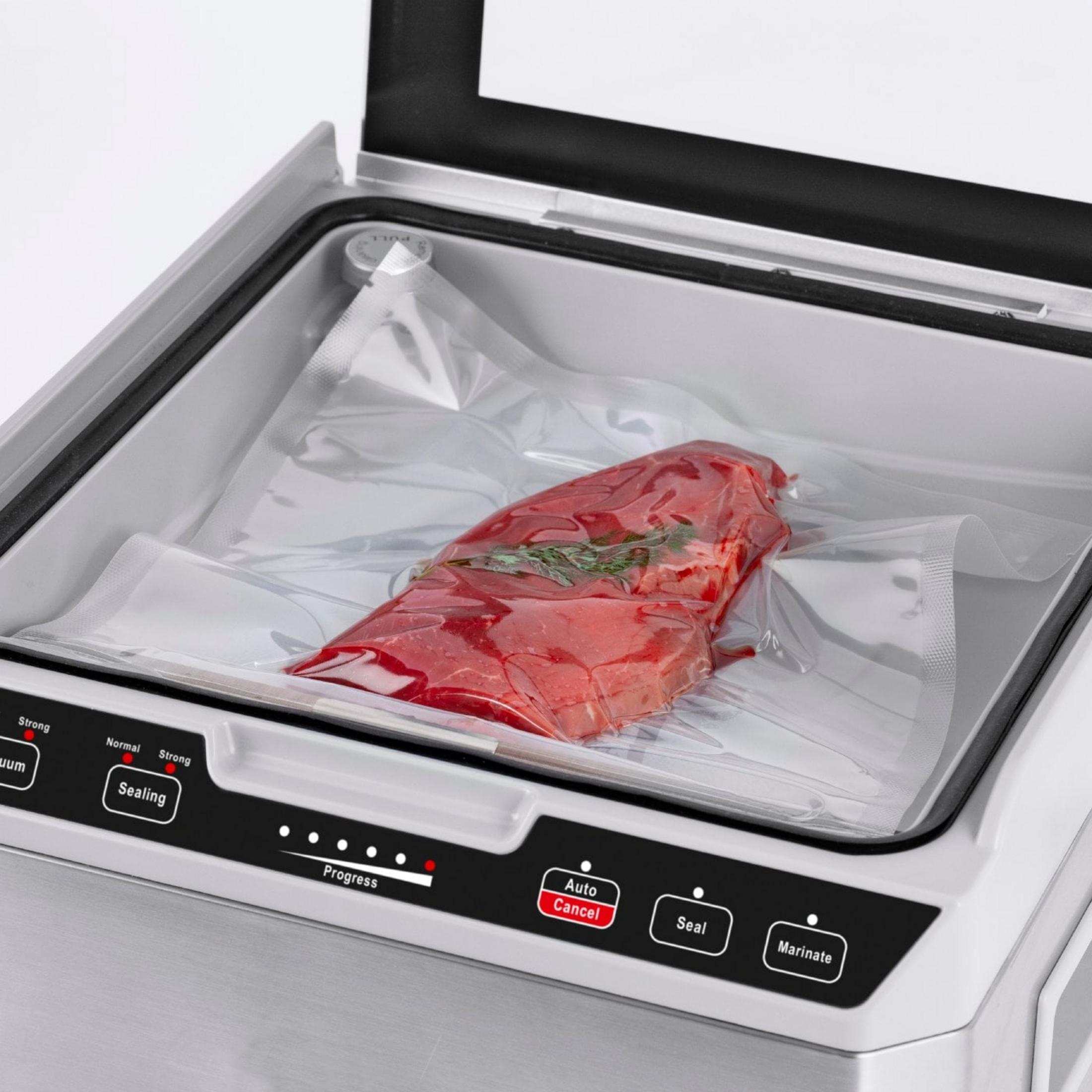 Ein rohes Stück Fleisch mit Kräutern in einem Vakuumierbeutel auf einem Vakuumiergerät.