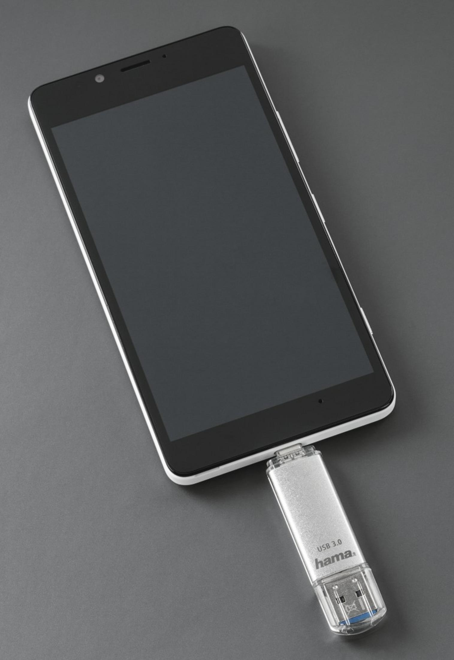 Une clé USB argentée est branchée sur un smartphone noir.