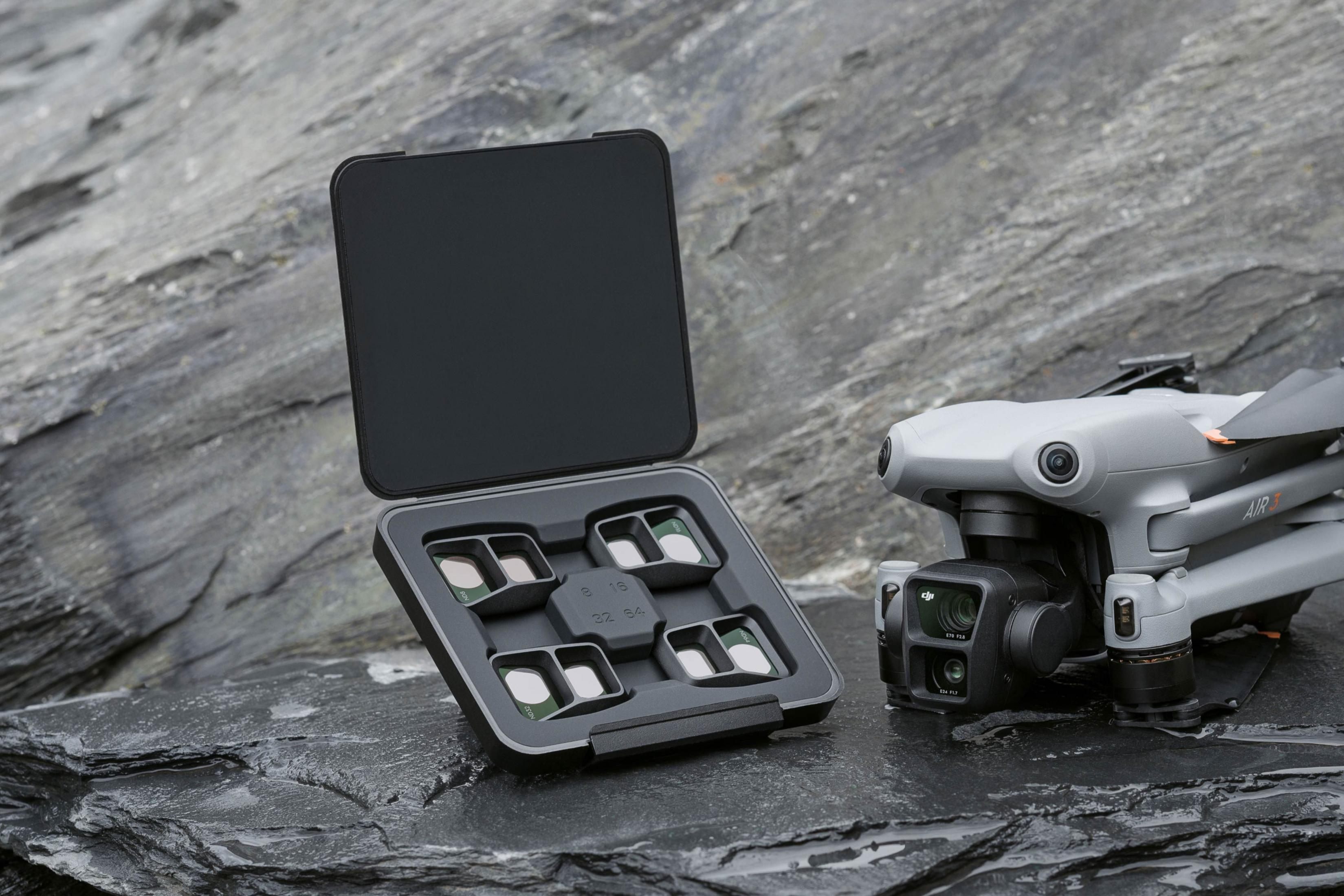 Un kit drone DJI Air 3 gris avec filtres sur pierre mouillée.