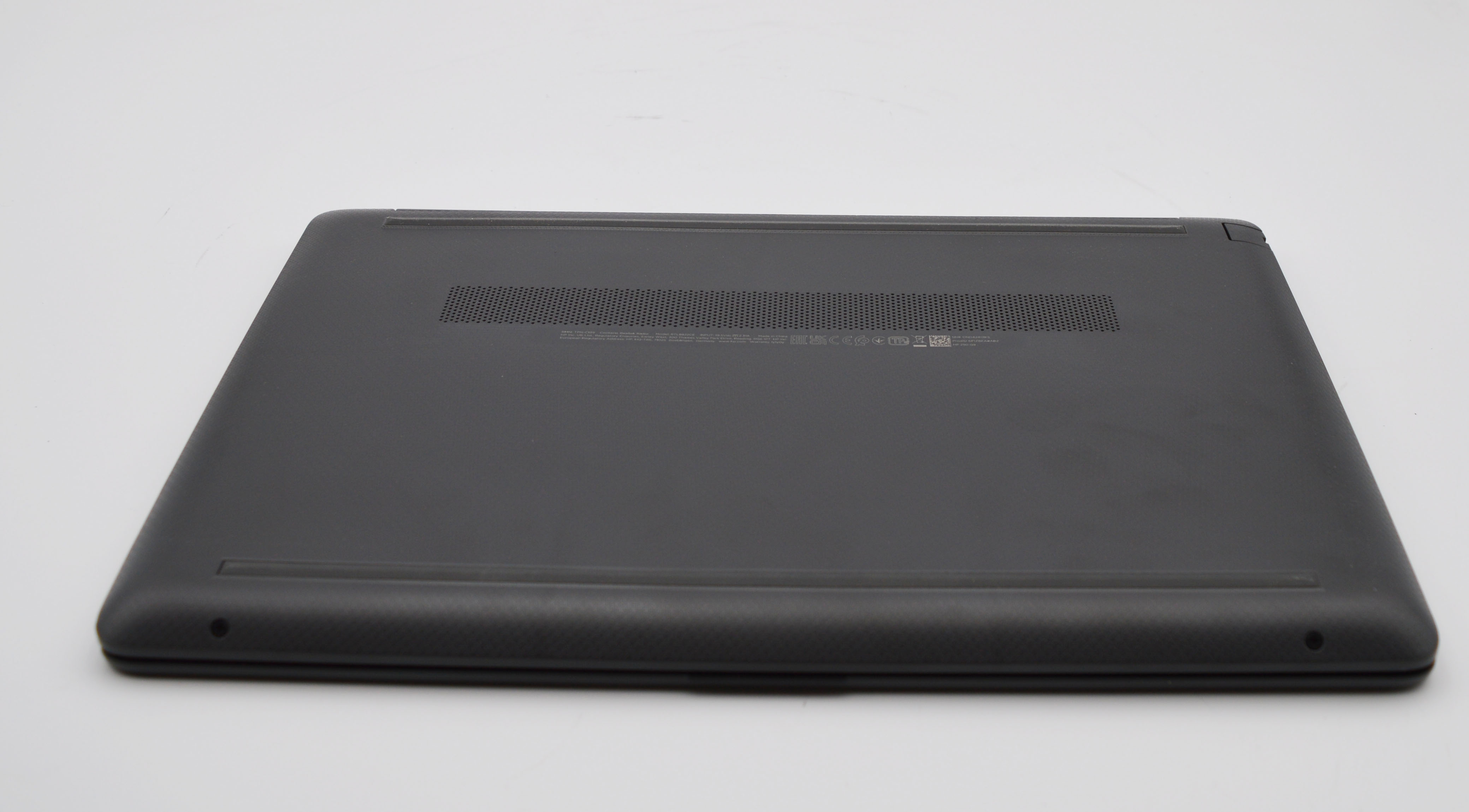 Rückseite eines dunklen Laptops mit Lüftungsschlitzen und Schrauben.