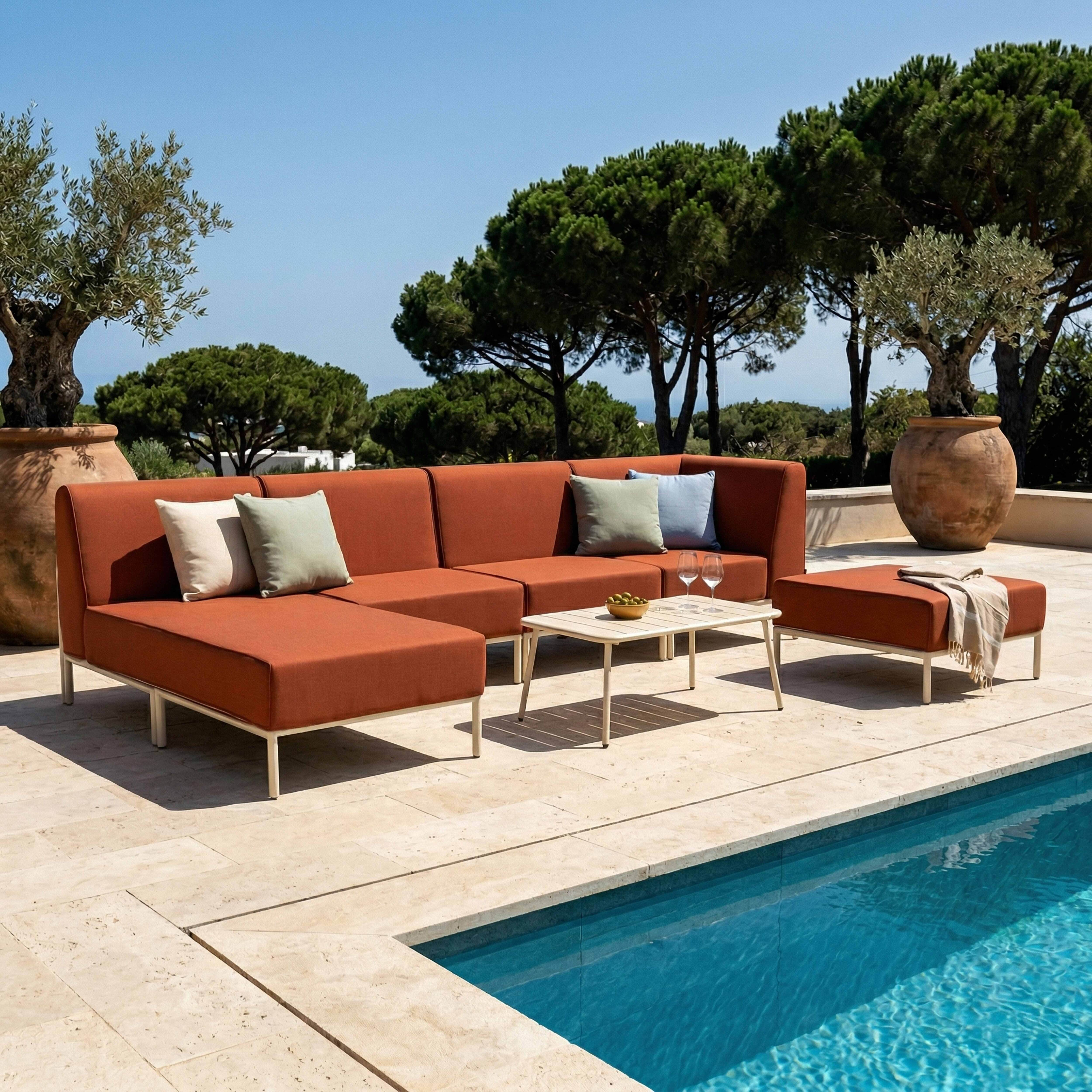 Außenlounge mit orangefarbenem Ecksofa am Pool, Couchtisch und Topfpflanzen.